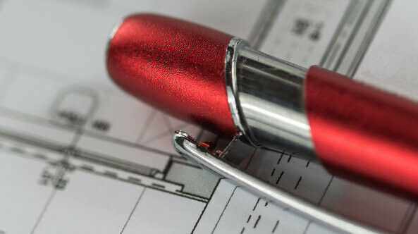 Roter PREFA Kugelschreiber liegt auf einem Plan
