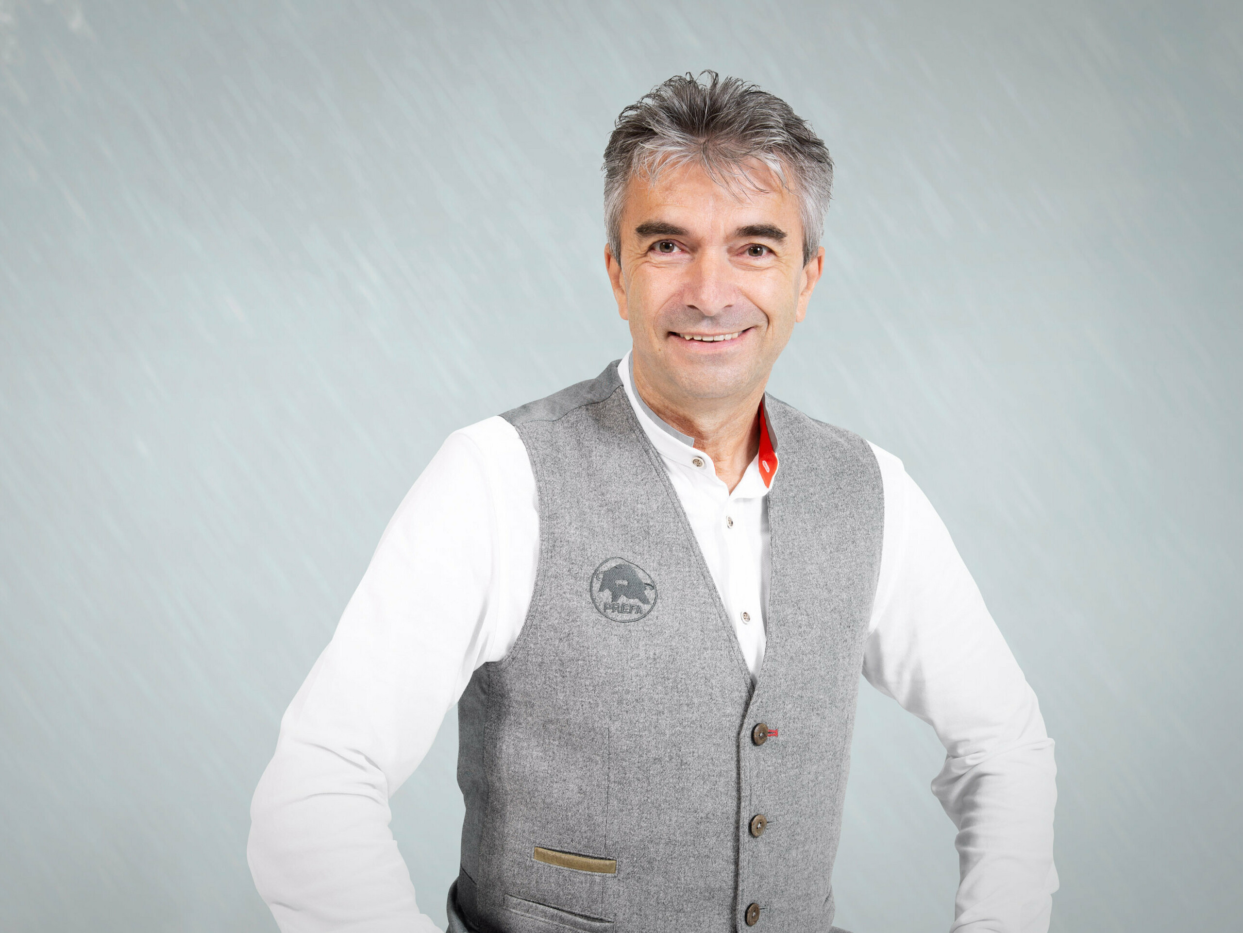 Porträt von Leo Höld, stellvertretender Leiter der PREFA Academy und tätig im Bereich der Produkttechnik. Leo trägt eine hellgraue Weste mit dem PREFA Logo und darunter ein weißes Hemd. 