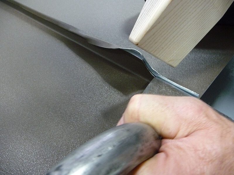 Den Traufenabschluss mittels Schaleisen und Holzhammer einfach verfalzen und umlegen.
