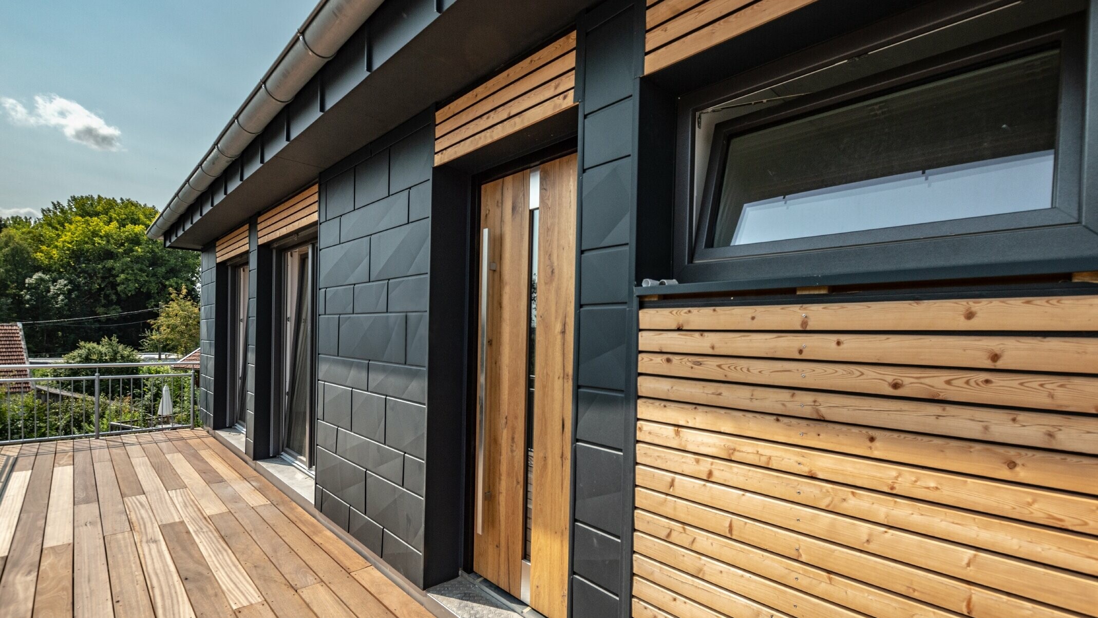 Fassadengestaltung durch Mischung der Materialien Aluminium - PREFA Siding.X in Anthrazit - und horizontalen Holzleisten.