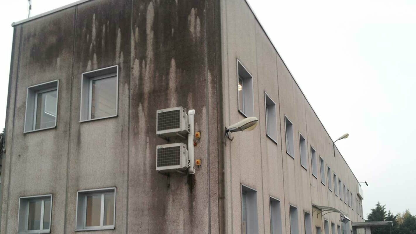 altes Industriegebäude vor der Fassadensanierung mit PREFA Sidings, starke Verfärbungen und Verschmutzungen an der Fassade