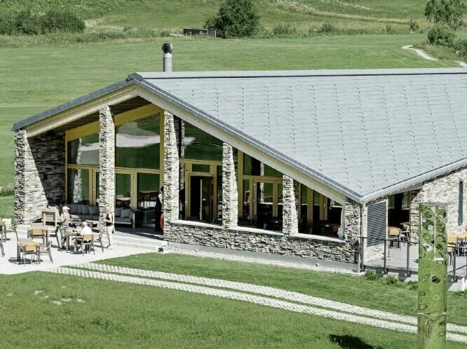 Der Golfclub in Andermatt inmitten der Schweizer Alpen eingedeckt mit PREFA Dachpaneelen FX.12 in P.10 Steingrau