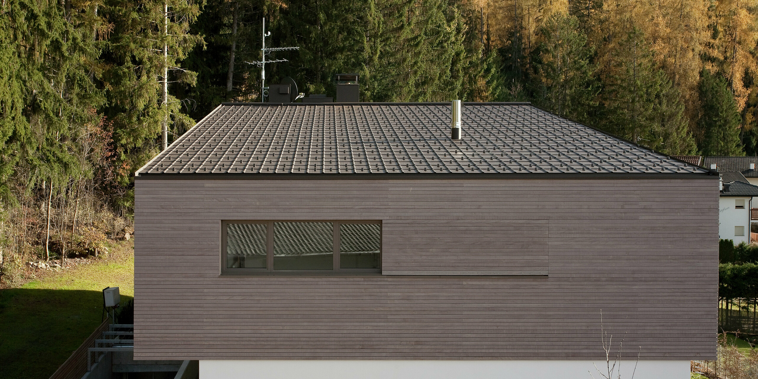 Dachansicht des modernen Gebäudes mit PREFA Dachplatten in P.10 Braun, die sich perfekt in die alpine Landschaft integrieren. Die klare Linienführung des Hauses und das zurückhaltende Design betonen die zeitlose Ästhetik.