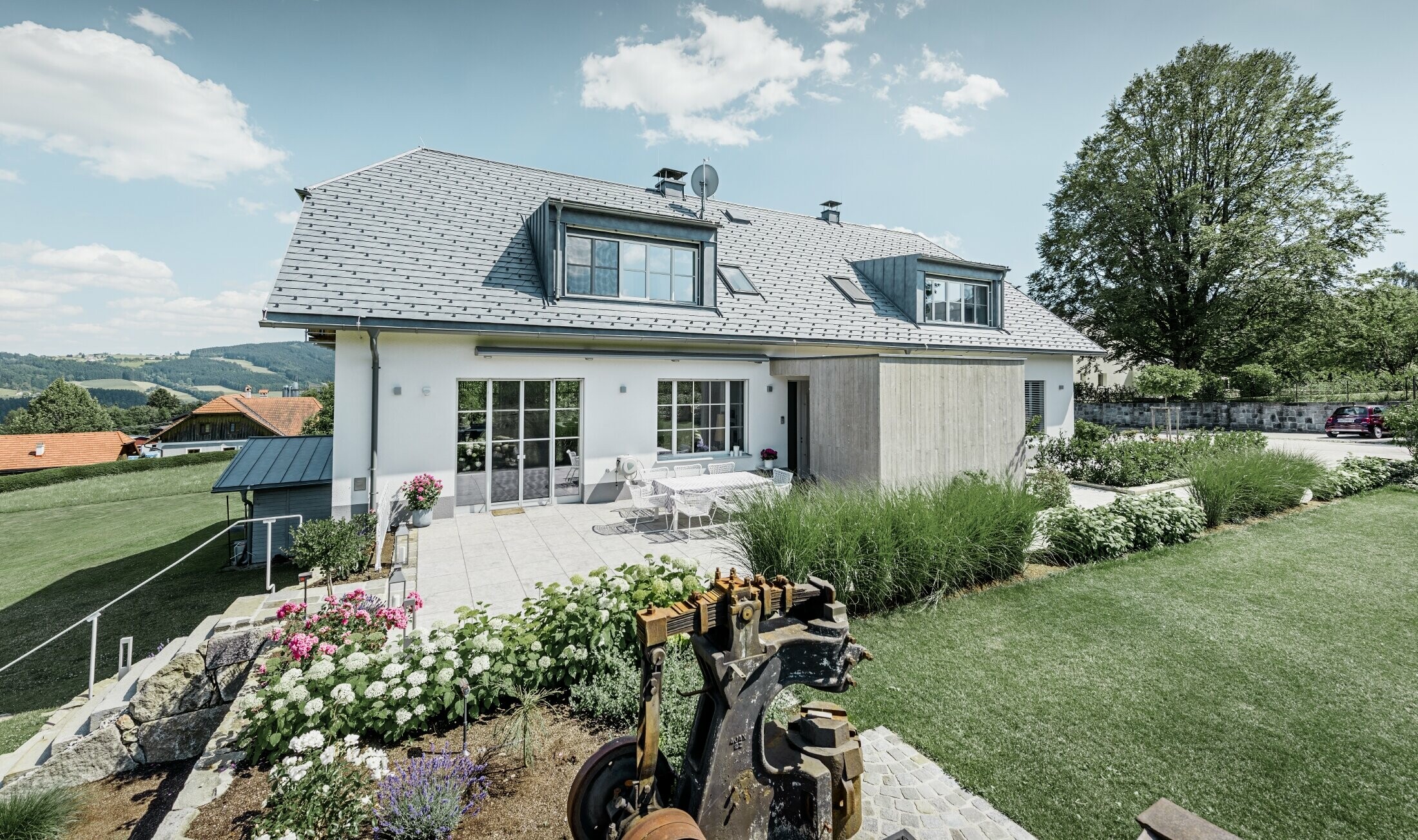 Klassisches Einfamilienhaus mit Krüppelwalmdach; Das Haus mit Dachsanierung mit der PREFA Dachschindel in Steingrau mit schön angelegtem Garten und großzügiger Terrasse.