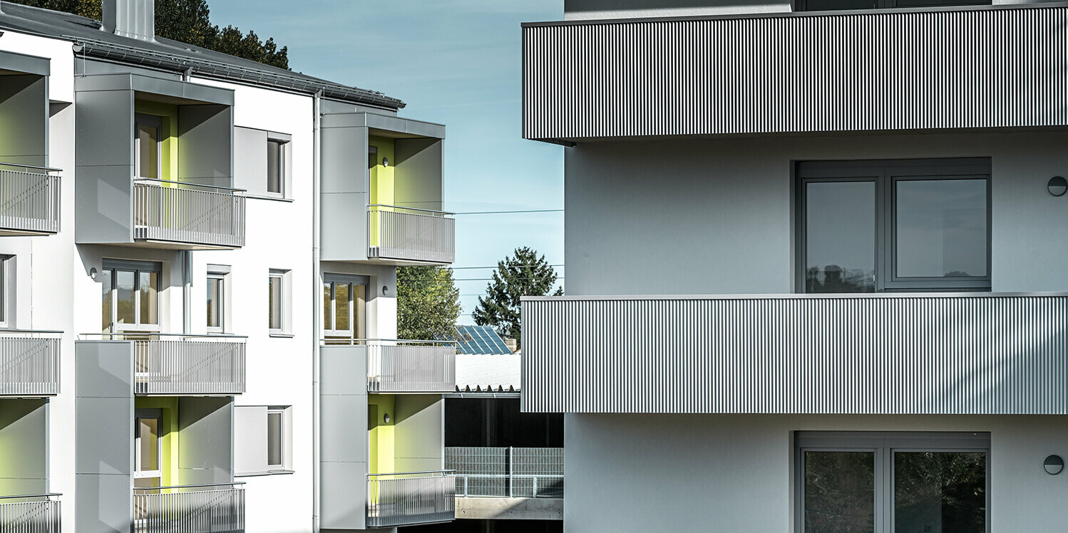 Nahaufnahme der Balkone der Glanzstoffsiedlung in St. Pölten, Niederösterreich. Die Balkone sind mit dem langlebigen PREFA Zackenprofil in der Farbe Silbermetallic verkleidet. Die Beschattung zeigt deutlich, wie sich das Zackenprofil durch Sonneneinstrahlung optisch verändert.