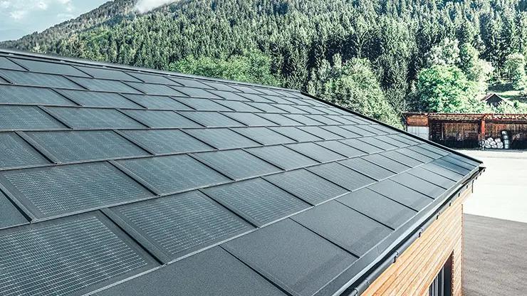 PREFA Solardachplatte in großer Ausführung kombiniert mit der Dachplatte R.16 in Schwarz, Kastenrinne und Lärchenholz-Fassade