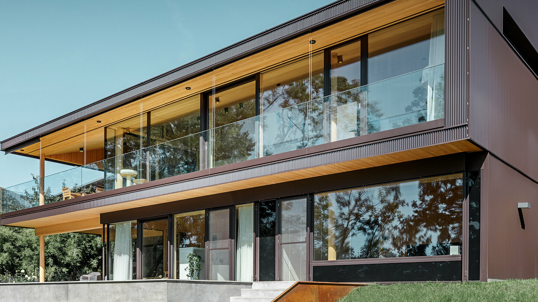Neues Einfamilienhaus mit großen Glasflächen und brauner Aluminium Fassade
