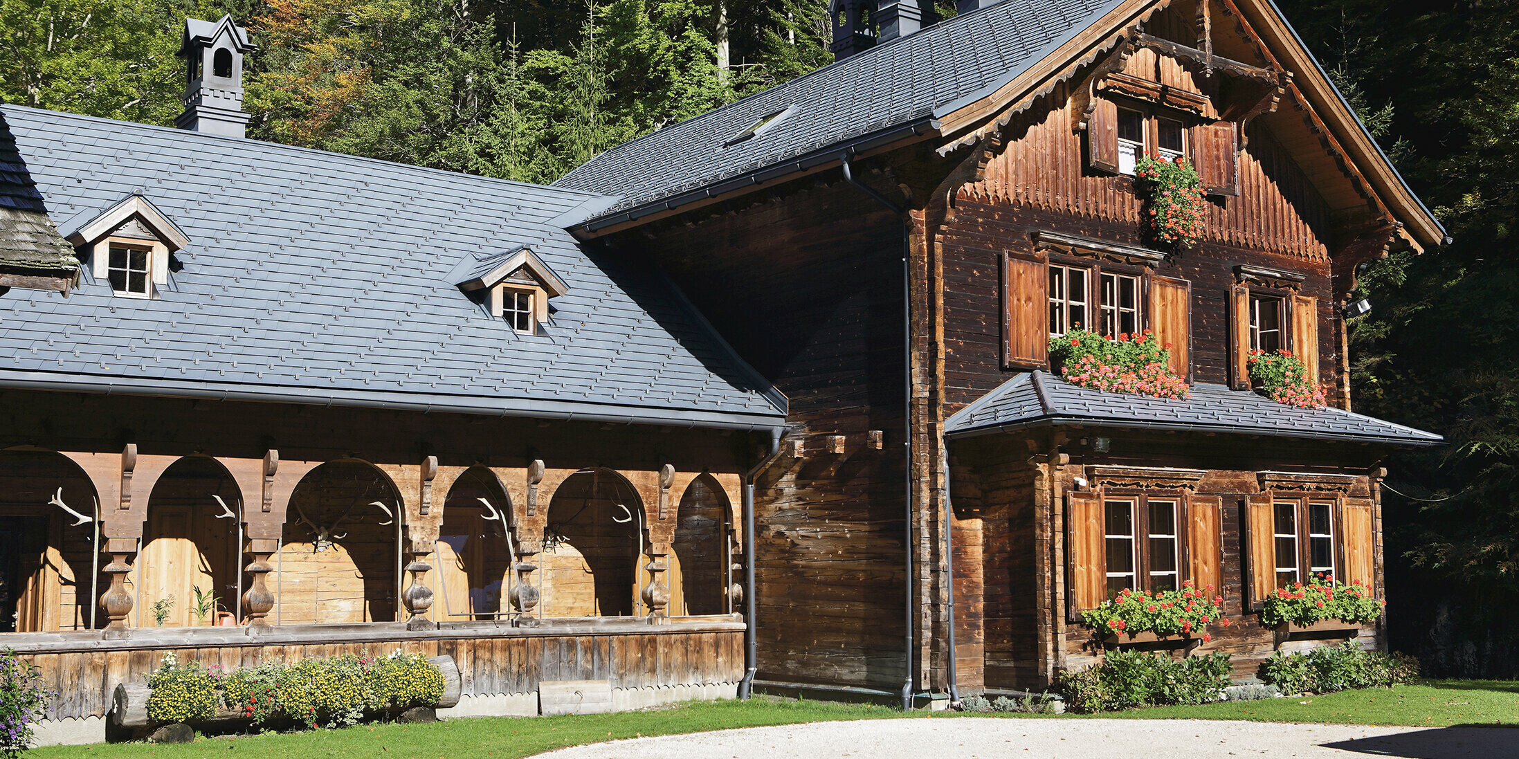Die rustikale Forst- und Jagdhütte in Gaming bei Langau, gedeckt mit PREFA Dachschindeln in P.10 Anthrazit, umgeben von grüner Natur und Wald.