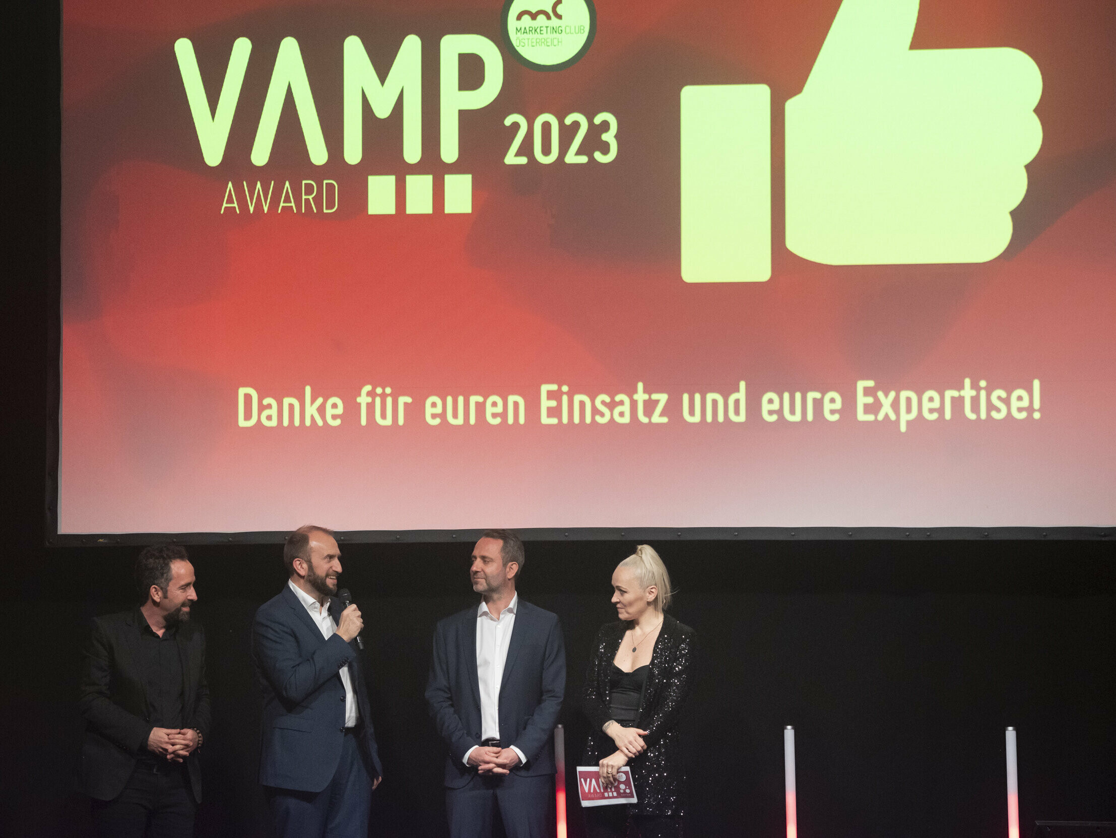 Foto von der Vamp Award Show 2023, im Vordergrund stehen 3 Moderatori:innen.