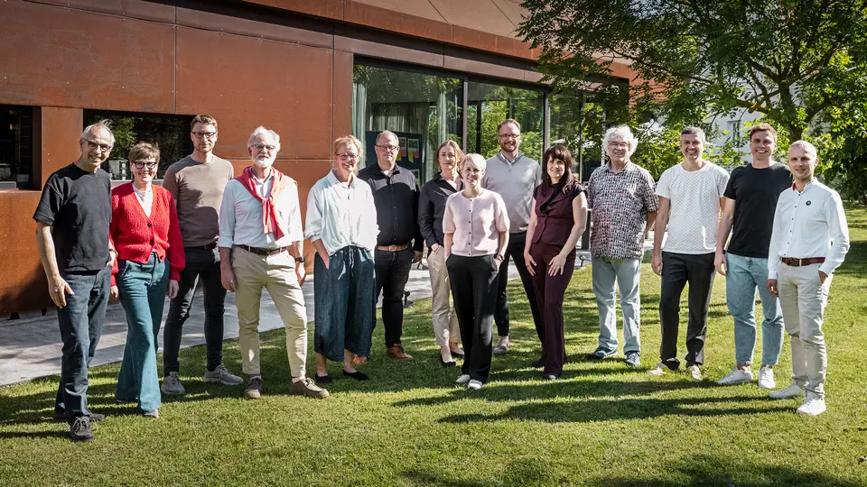 Gruppe von Architektur-Experten vor einer modernen Winzerresidenz im Seewinkel. Das Bild wurde inszeniert vor einem markanten, rostfarben schimmernden Gebäude mit klaren Linien und großzügigen Glasflächen. Die metallische Oberfläche reflektiert das Licht und setzt einen starken, visuellen Akzent in der natürlichen Umgebung. 
