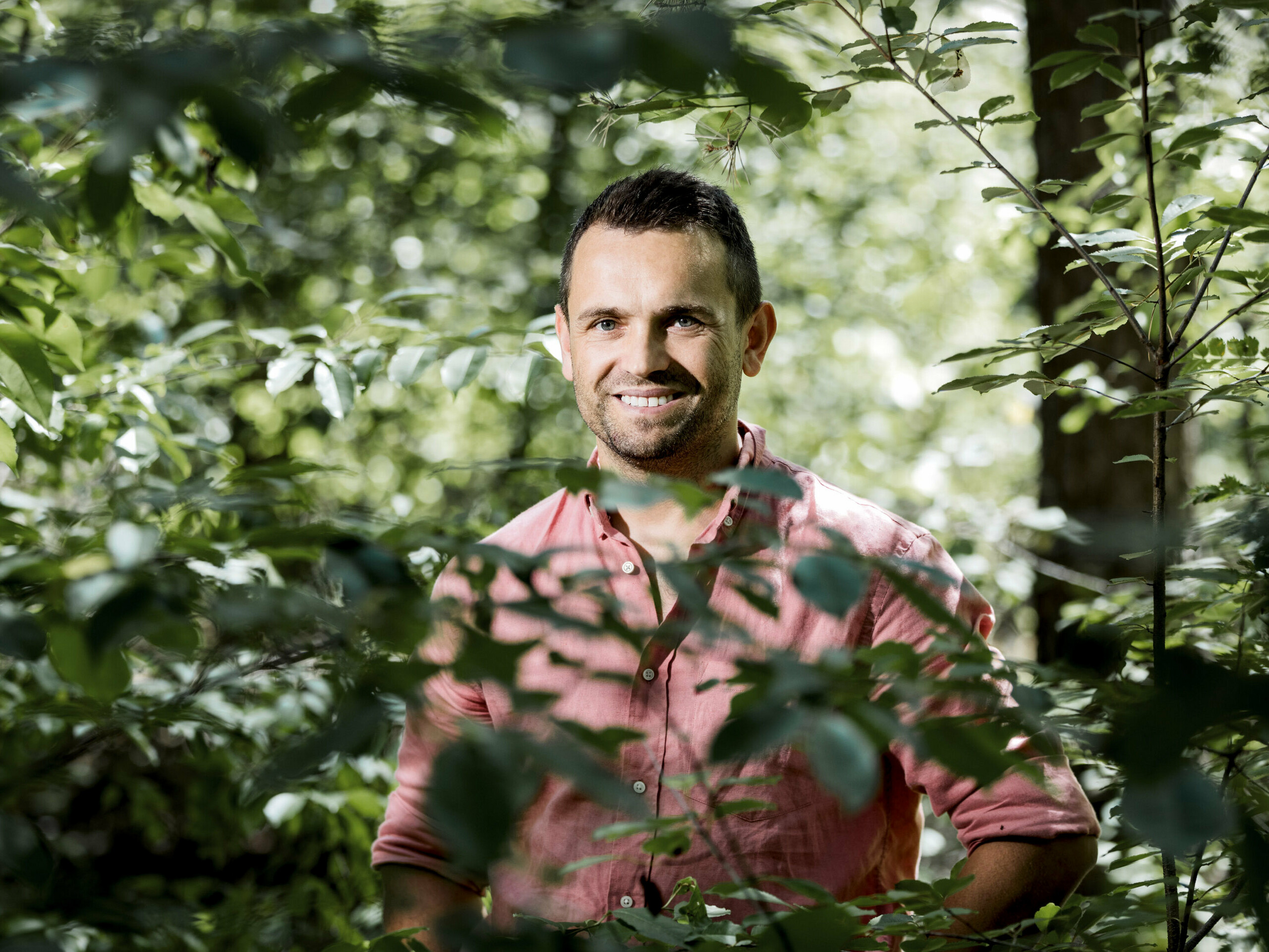 Portrait vom Besitzer der Boroteka Rafał Stramski, lächelnd im Wald.