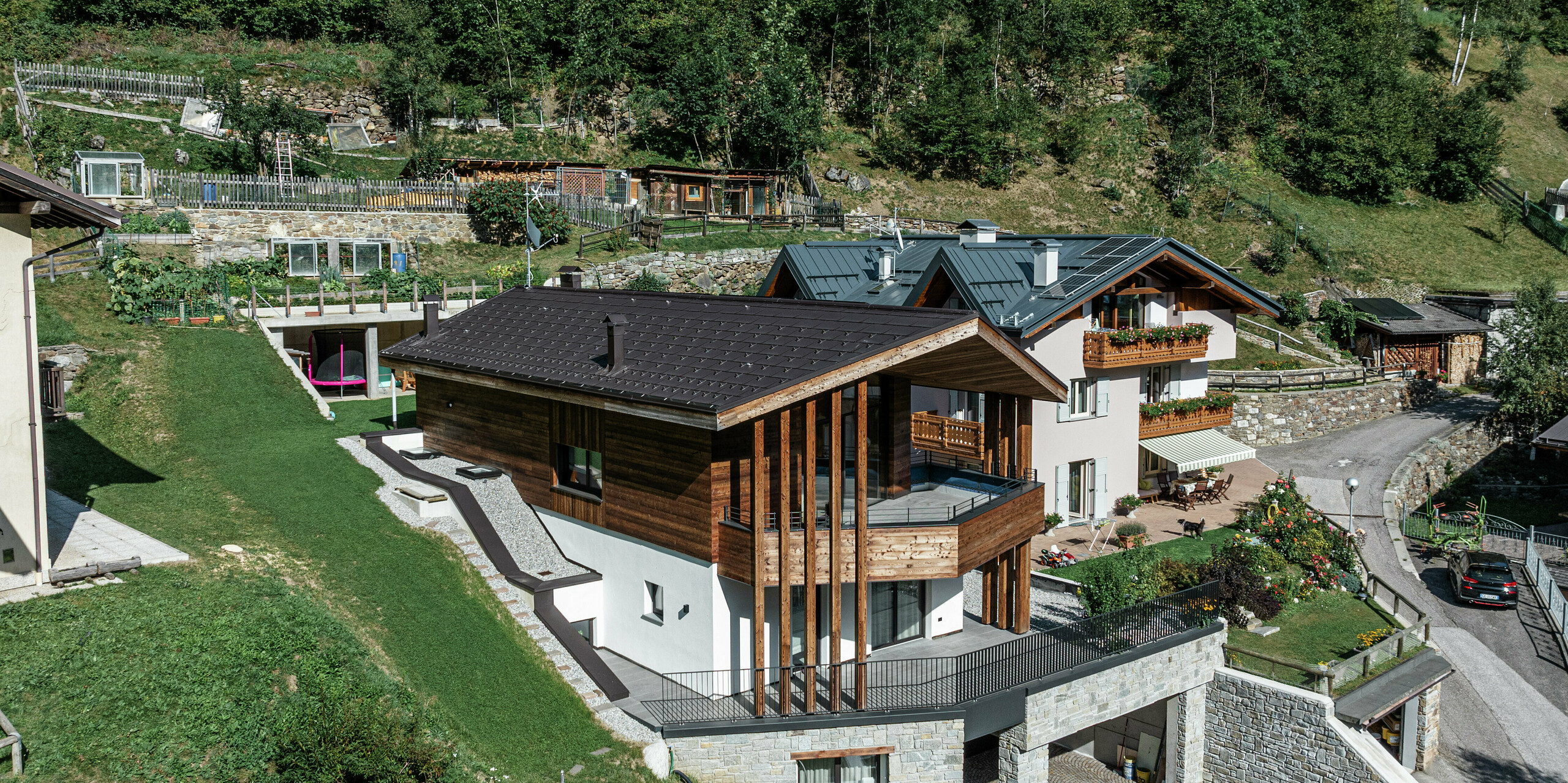 Die Voderseite des modernen Berghauses in Cogolo, Val di Sol, beeindruckt durch die Kombination von Holzarchitektur und dem widerstandsfähigen PREFA Aluminiumdach in der hochwertigen Beschichtung P.10 Braun. Die Dachplatte R.16 aus hochwertigem Blech schützt zuverlässig vor extremen Witterungseinflüssen und fügt sich harmonisch in die alpine Umgebung ein. Eine langlebige, elegante und wartungsarme Lösung für anspruchsvolle Bergregionen.