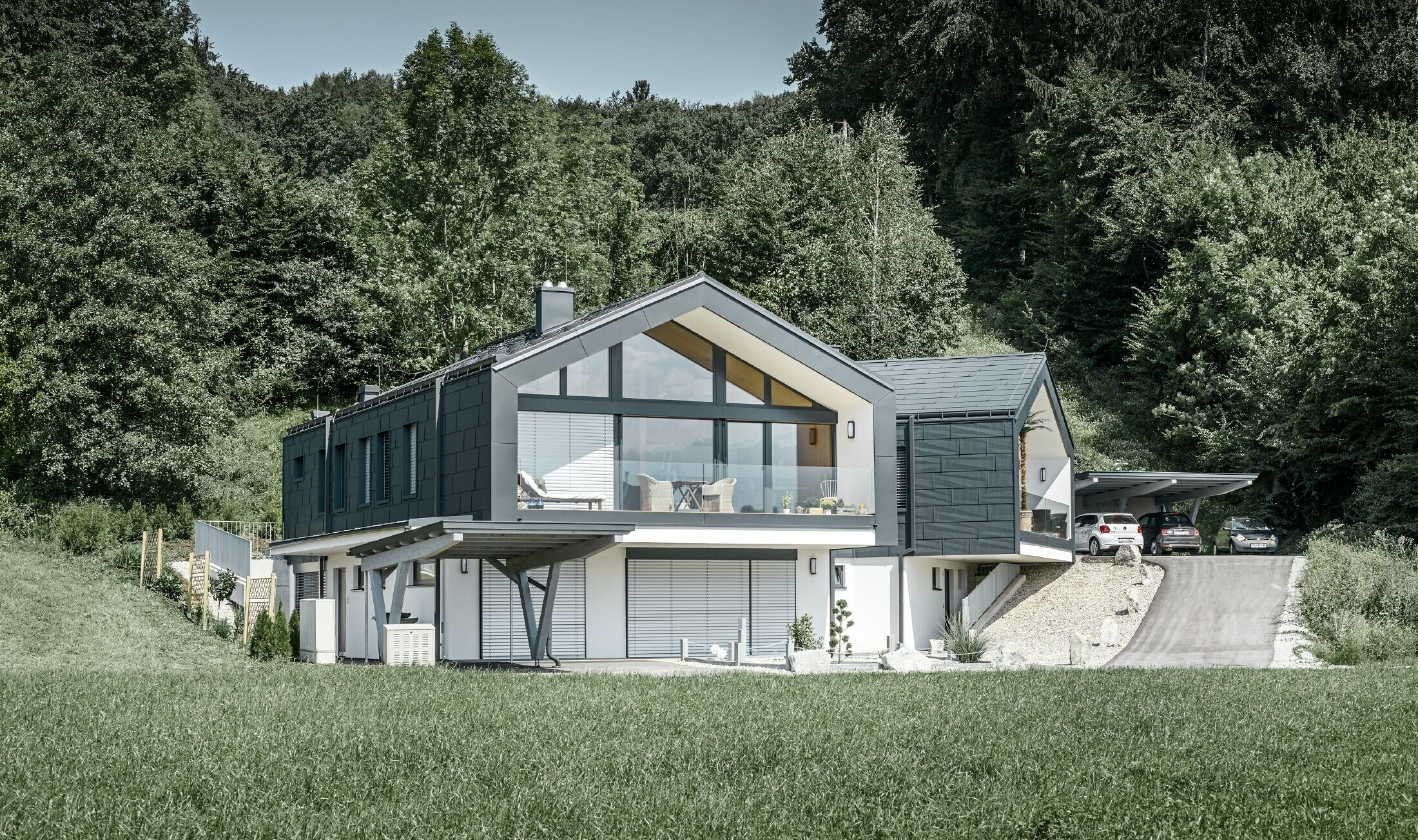 Modernes Mehrfamilienhaust mit einer großen Fensterfront, Dach und Fassade wurden mit dem Dach- und Fassadenpaneel FX.12 in anthrazit von PREFA bekleidet