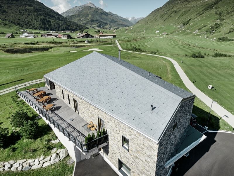 Ansicht von oben auf das Dach eines Golfclubs inmitten der Schweizer Alpen, eingedeckt mit FX.12 Dachpaneelen
