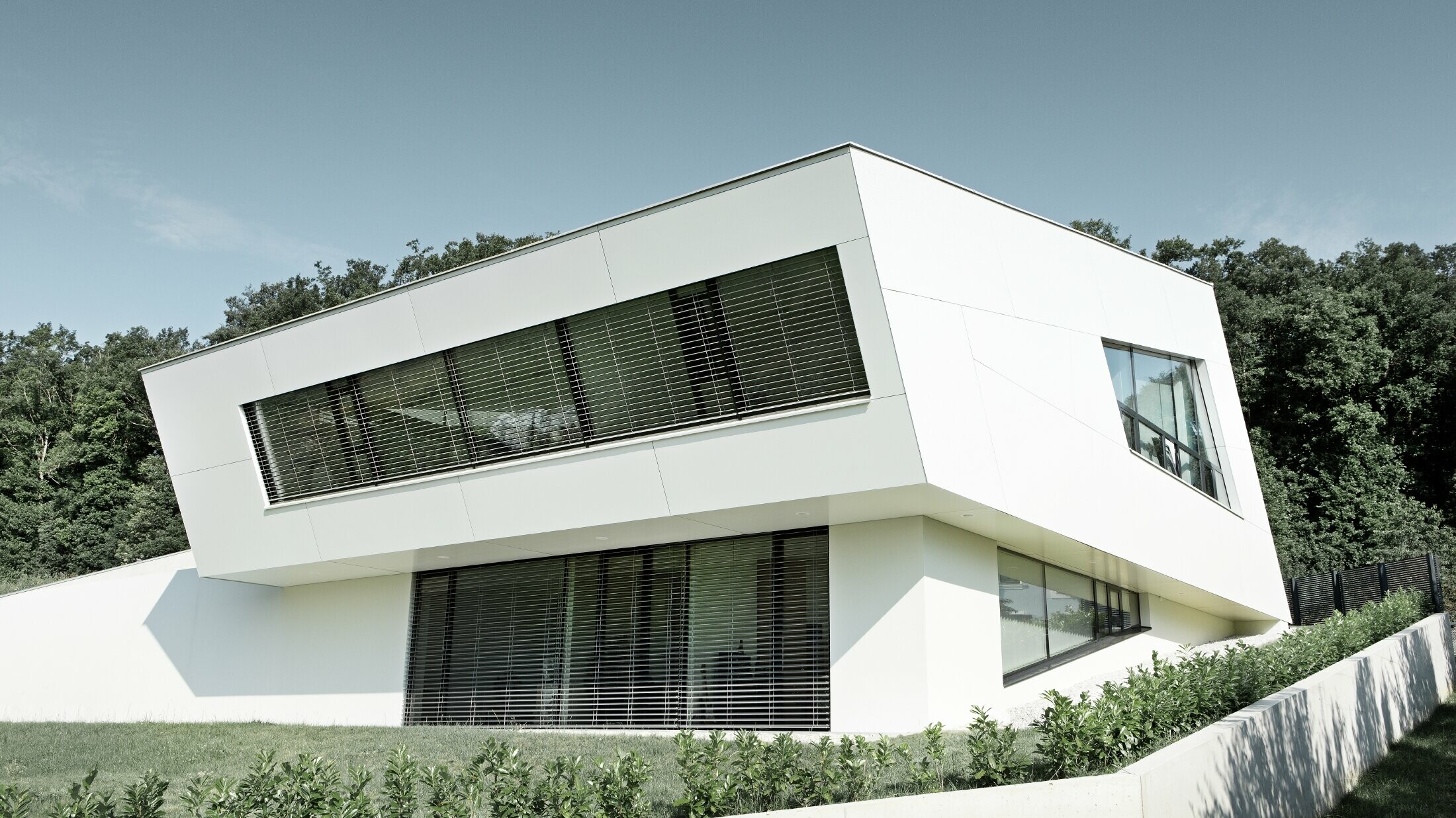 Sehr modernes Einfamilienhaus mit weißer PREFA Verbundplattenfassade und großen Fenstern