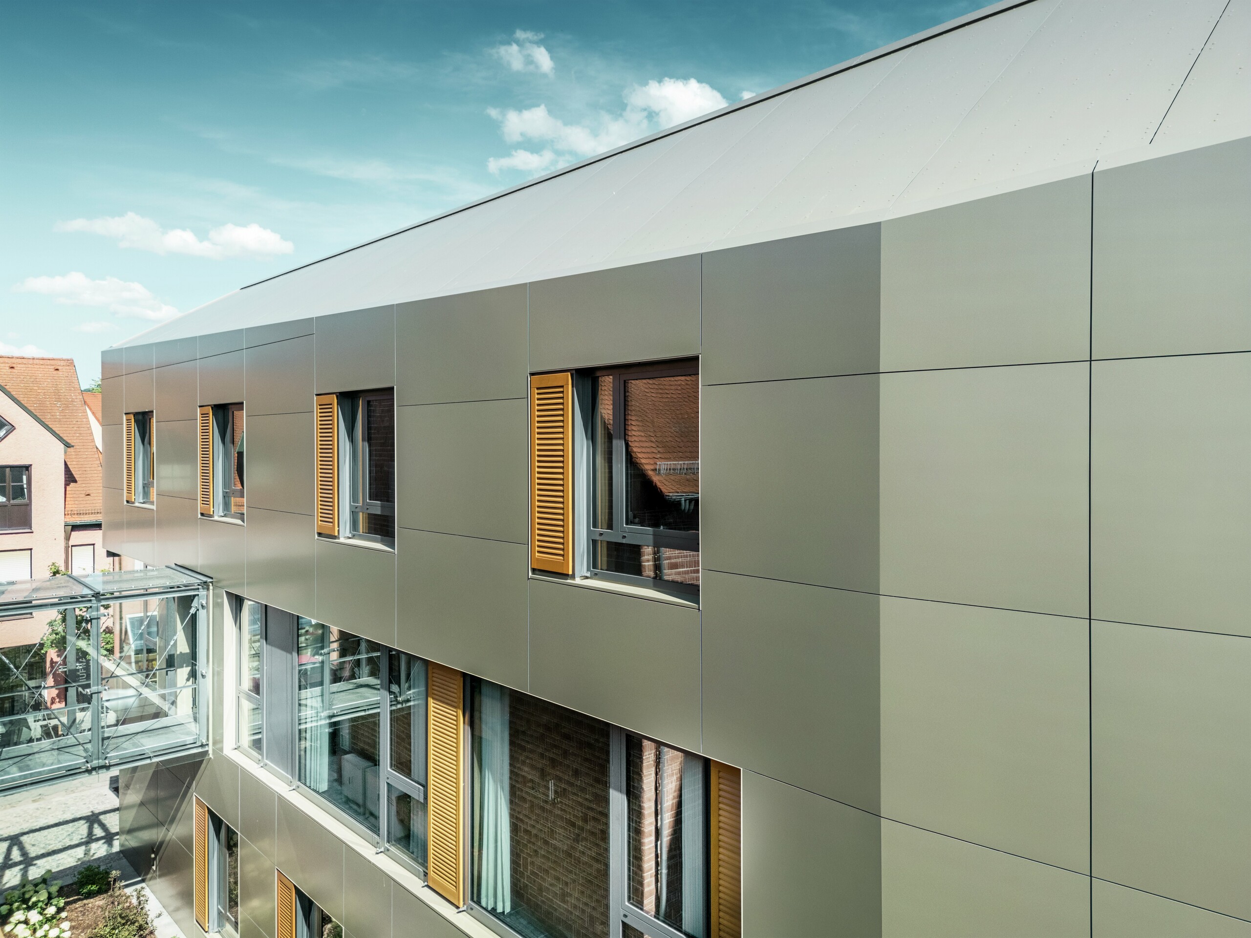 Das Bild zeigt einen Ausschnitt der Fassade des Rathauses in Alzenau, Deutschland, mit Aluminium-Verbundplatten von PREFA in Bronze. Die Platten sind in einem modernen, rechteckigen Muster verlegt.