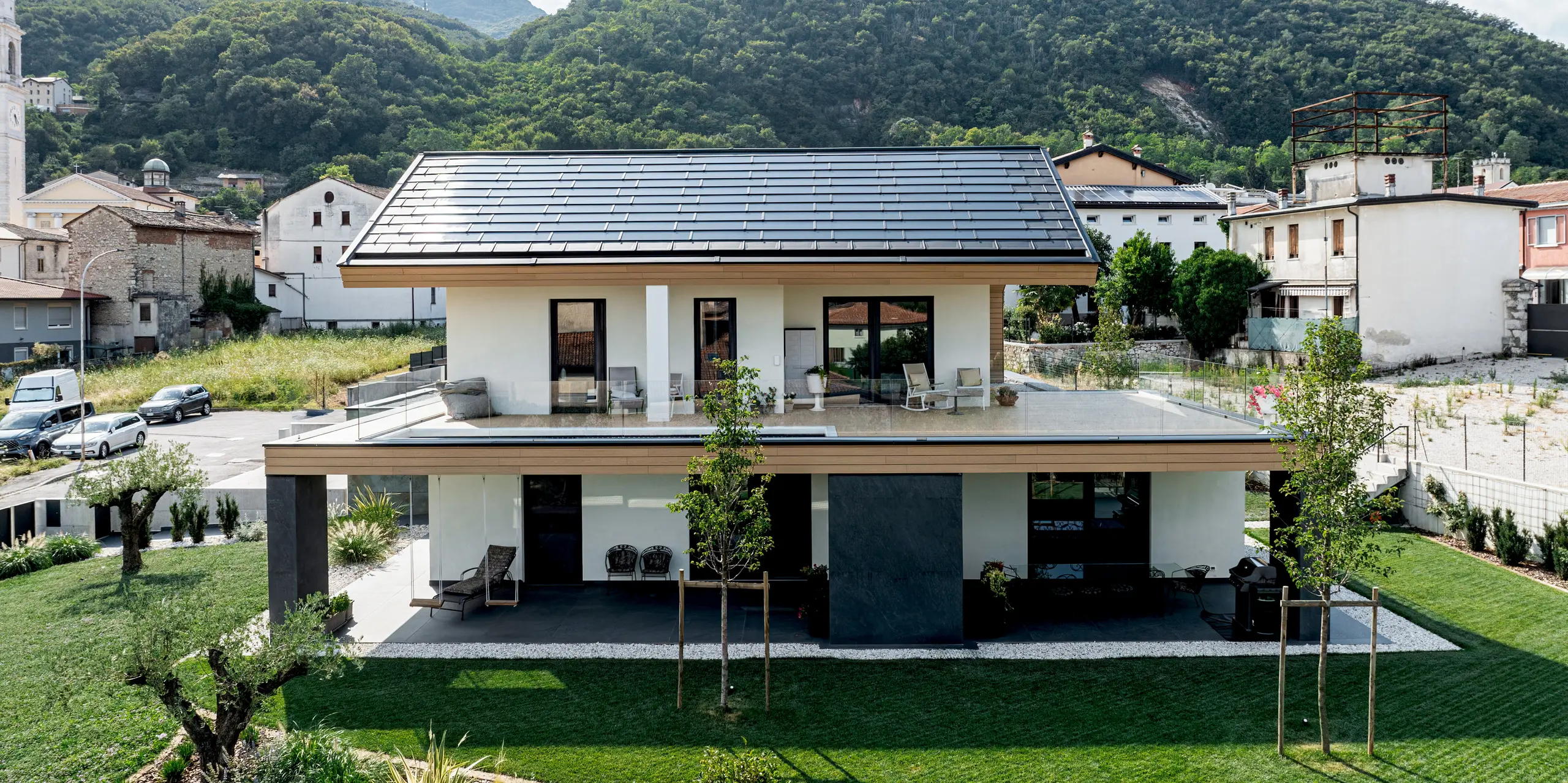 Großzügiges Einfamilienhaus in Vicenza mit moderner Aluminiumverkleidung aus PREFA Solardachplatte und Dachplatte R.16 in P.10 Schwarz. Das hochwertige Blechdach fügt sich harmonisch in die Berglandschaft ein und verbindet zeitloses Design mit nachhaltiger Energiegewinnung. PREFA Produkte bieten langlebigen Schutz, hohe Widerstandsfähigkeit und eine stilvolle architektonische Lösung.