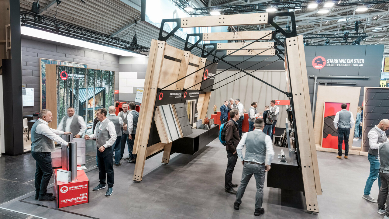 Belebter PREFA Messestand mit Messewänden mit den PREFA Aluminium Dachprodukten und Fassadenprodukten.