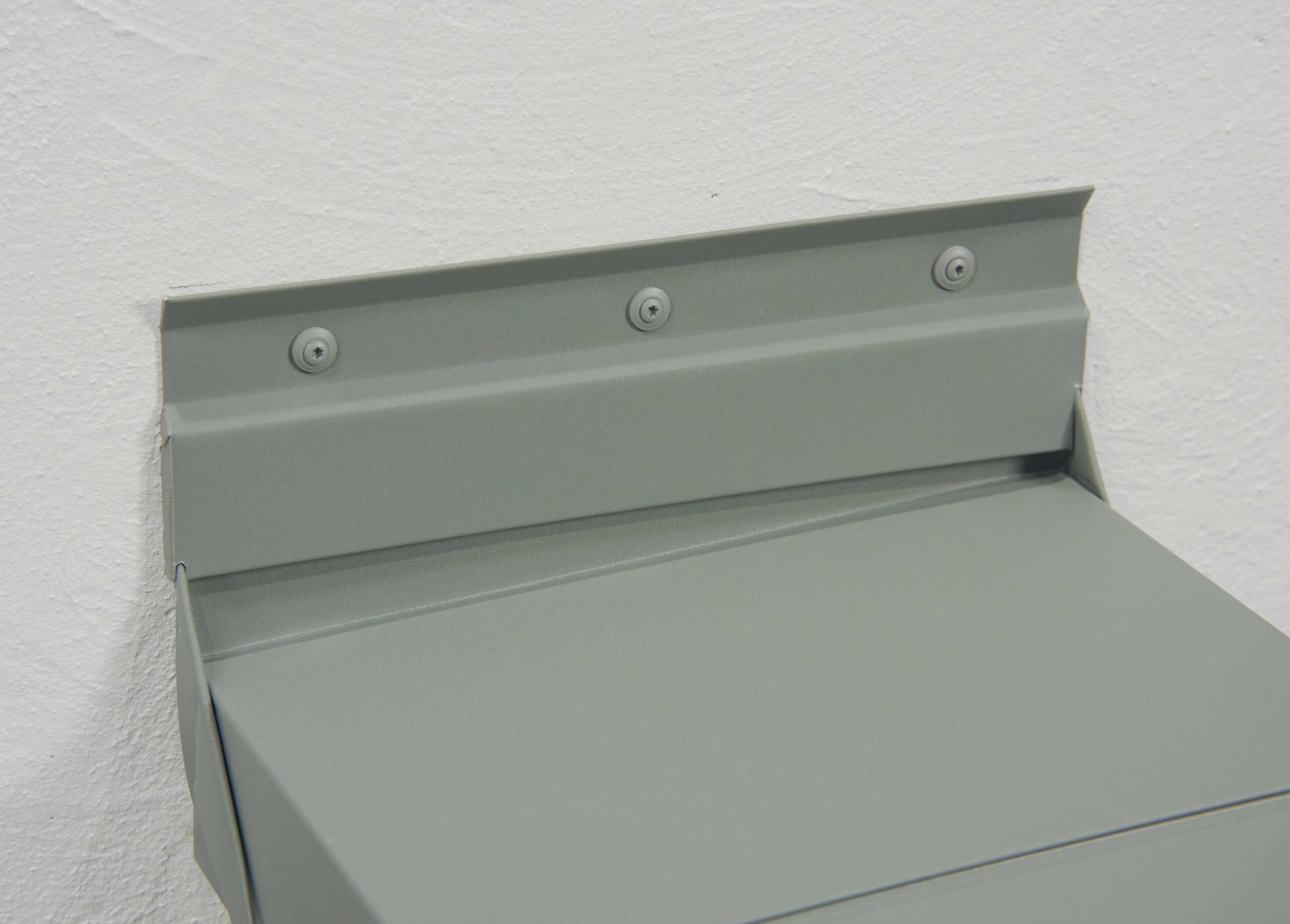 Seitlicher Anschluss einer PREFA Attikaabdeckung aus Aluminium mit Kittleiste und sichtbarer Verschraubung an der Wand