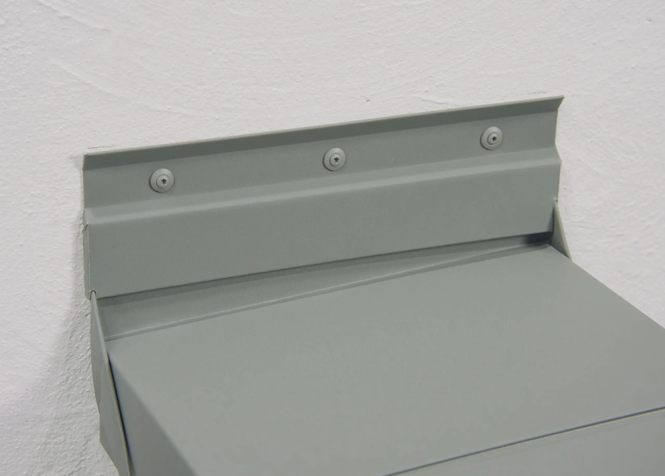 Seitlicher Anschluss einer PREFA Attikaabdeckung aus Aluminium mit Kittleiste und sichtbarer Verschraubung an der Wand
