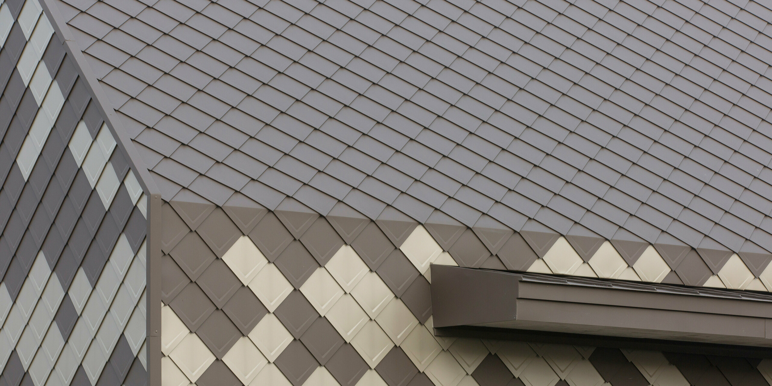 Detailansicht auf die Gebäudekanten des Horts in Sessenheim mit einer einprägsamen Hülle aus PREFA Dach- und Wandrauten  29 × 29 in den Farben P.10 Braun sowie Bronze