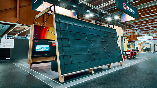 Modernes Solardachsystem am PREFA Messestand 2026: Präsentiert wird die innovative PREFA Solardachplatte, die Dachdeckung und Photovoltaik in einem Produkt vereint. Die in die Aluminium-Dachfläche integrierten Module bieten eine ästhetische, dachparallele Lösung für nachhaltige Energiegewinnung – robust, langlebig und sturmsicher. Der großflächige Aufbau zeigt die harmonische Optik sowie die hochwertige Verarbeitung. Im Hintergrund ergänzt ein interaktiver Bildschirm mit dem PREFA Konfigurator die Produktpräsentation. Diese Kombination aus Technik, Design und digitaler Beratung macht den PREFA Stand zum Anziehungspunkt für zukunftsorientiertes Bauen mit Fokus auf Klimaschutz und Energieeffizienz.