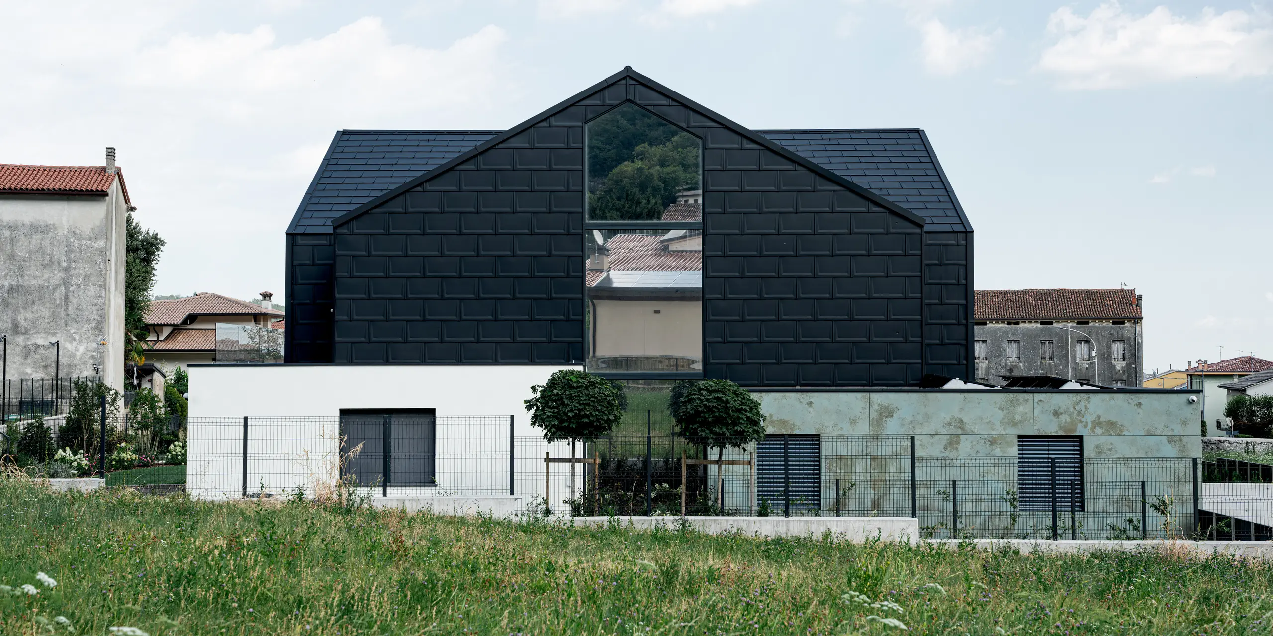 Markantes Einfamilienhaus in Vicenza mit markanter PREFA Dachplatte R.16 an Dach und Fassade in P.10 Schwarz. Die dunkle Aluminiumhülle betont die klare Gebäudeform und bildet einen spannenden Kontrast zur natürlichen Umgebung. PREFA Aluminiumprodukte stehen für langlebige Qualität, hohe Widerstandsfähigkeit und zuverlässigen Schutz bei gleichzeitig zeitgemäßer Architektur.
