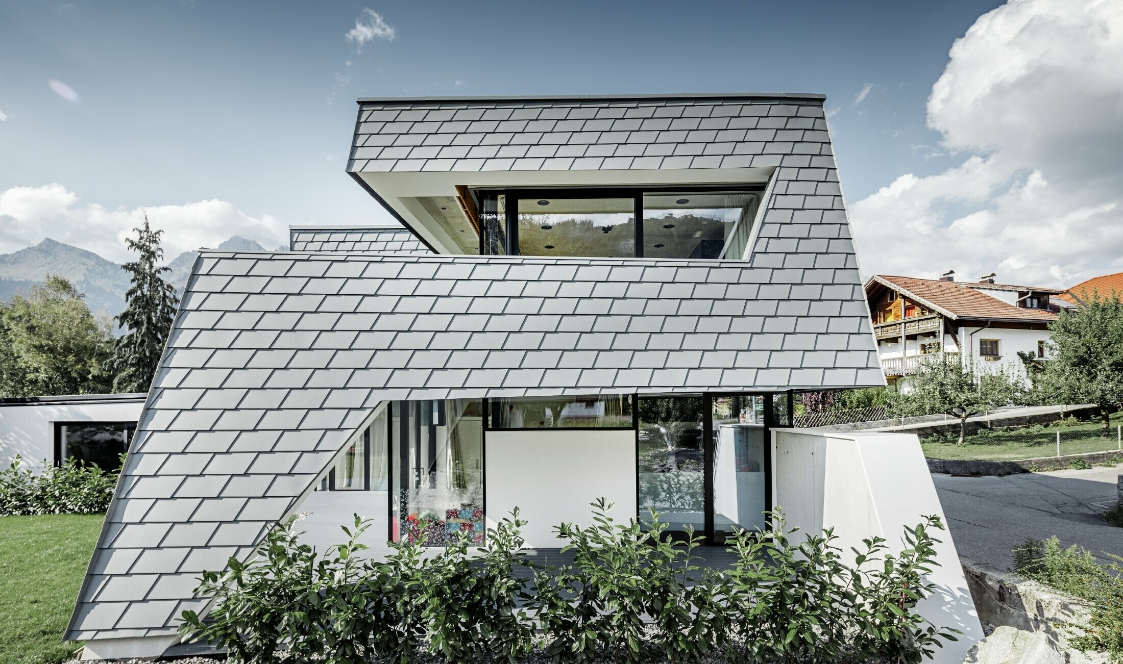 modernes Einfamilienhaus mit Flachdach, großen Fensterflächen und einer Schindel-Fassade in hellgrau aus Aluminium von PREFA