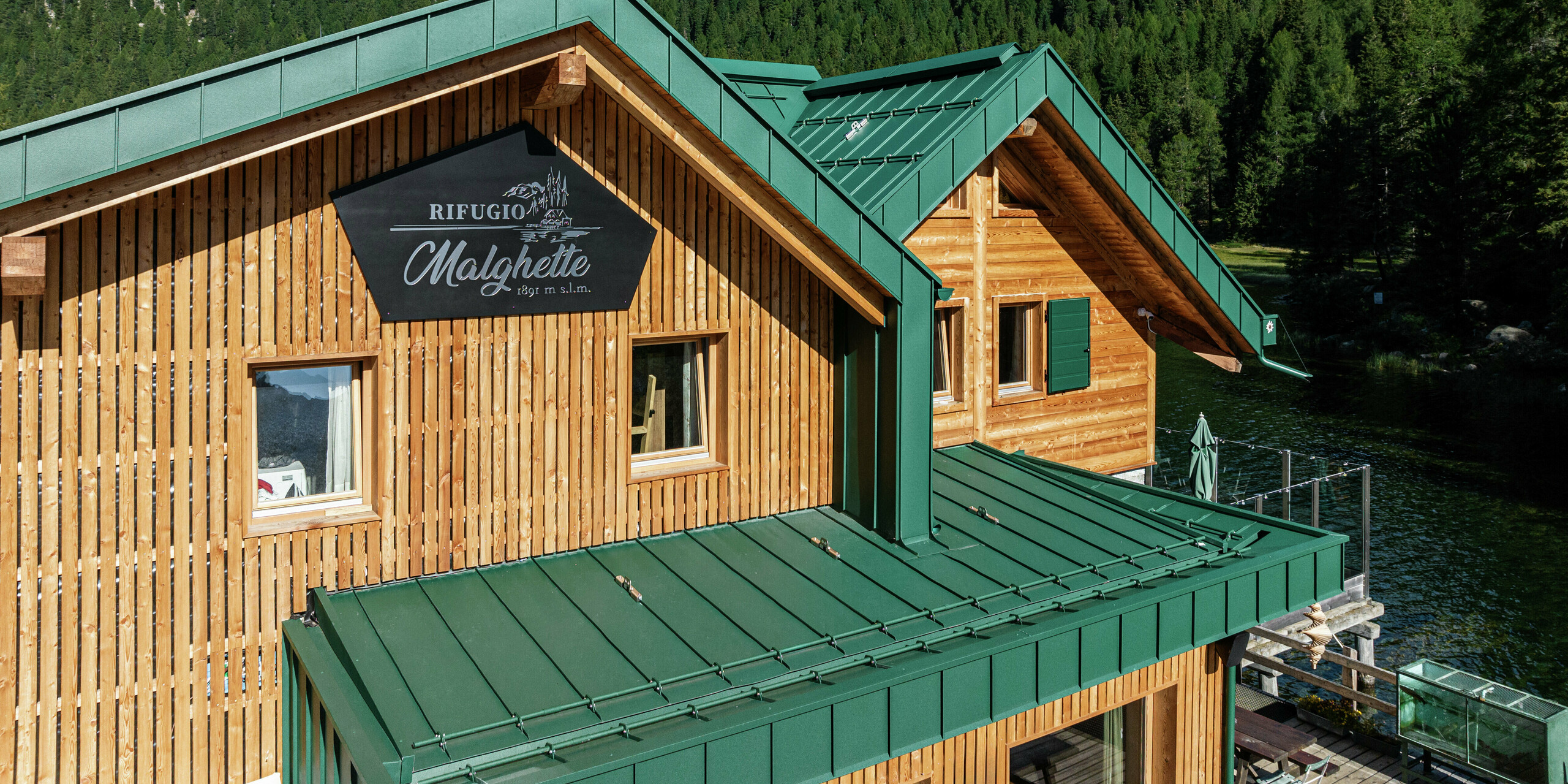 Detailansicht der beiden Giebel des Rifugio Malghette. Die Holzfassade wurde mit PREFALZ an Dach und Fassade umrahmt - langlebig, sturmsicher und perfekt für extreme Wetterbedingungen. Die hochwertige Aluminiumverkleidung im Farbton P.10 Moosgrün fügt sich harmonisch in die alpine Landschaft ein und schützt die Hütte zuverlässig auf 1.888 m Höhe.