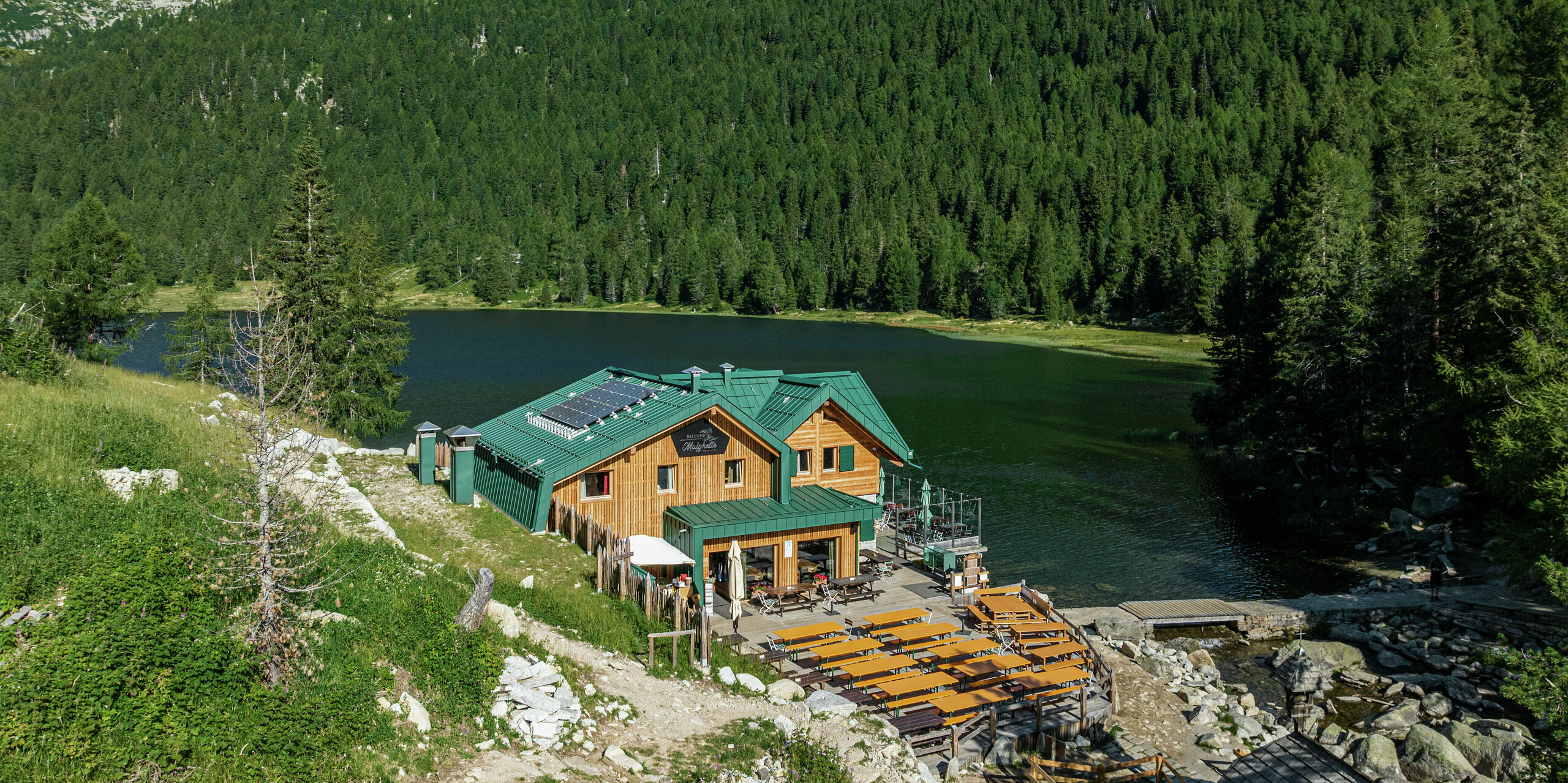 Das Rifugio Malghette auf 1.888 m, idyllisch am See gelegen, mit dem PREFALZ Dach in P.10 Moosgrün - wetterfest, langlebig und perfekt in die Natur integriert. Die großzügige Sonnenterrasse lädt Wanderer zum Verweilen ein, das widerstandsfähige Aluminiumdach trotzt selbst extremem Bergwetter.