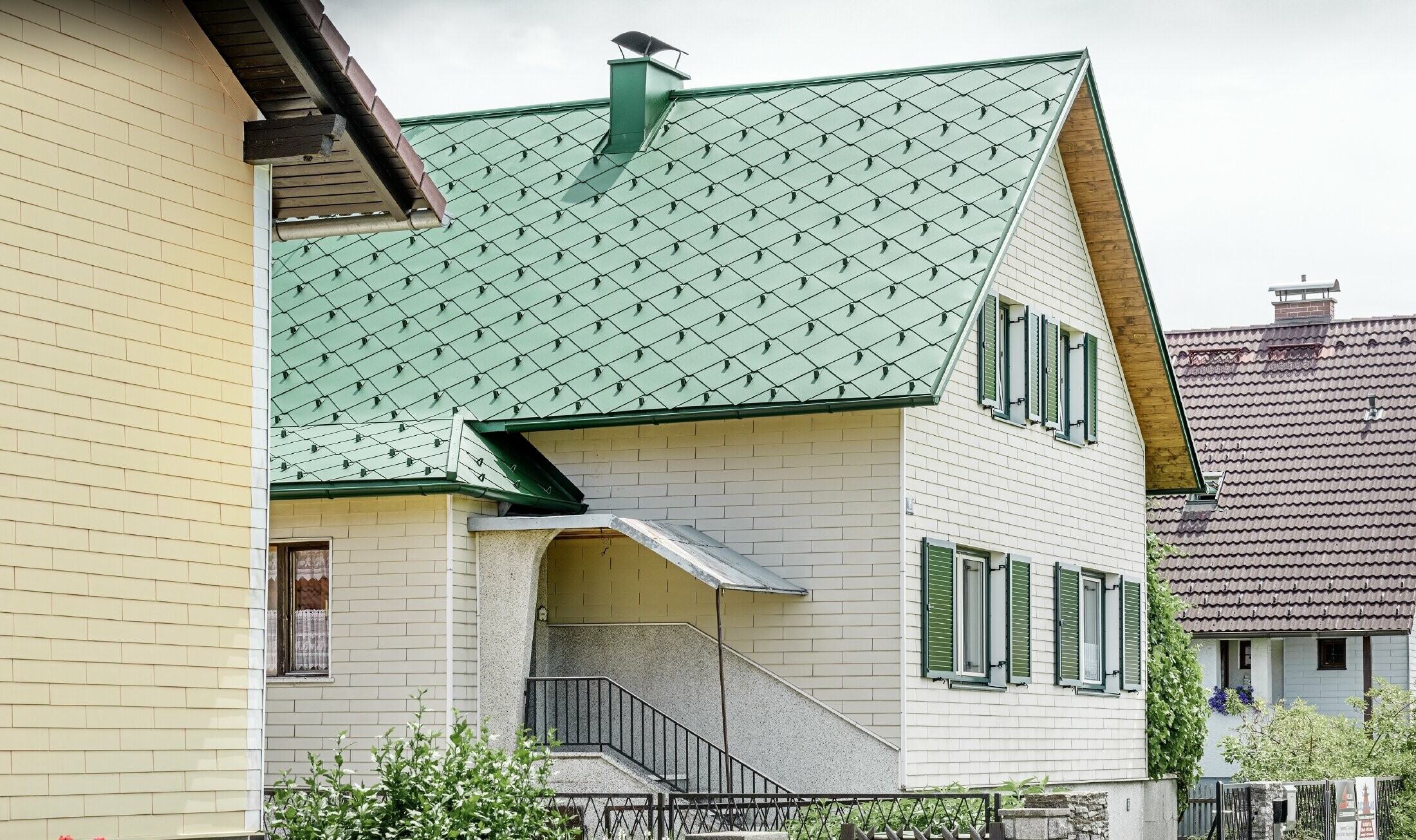 Klassisches Einfamilienhaus mit Satteldach mit einer Dacheindeckung aus Aluminium von in moosgrün mit grünen Fensterläden