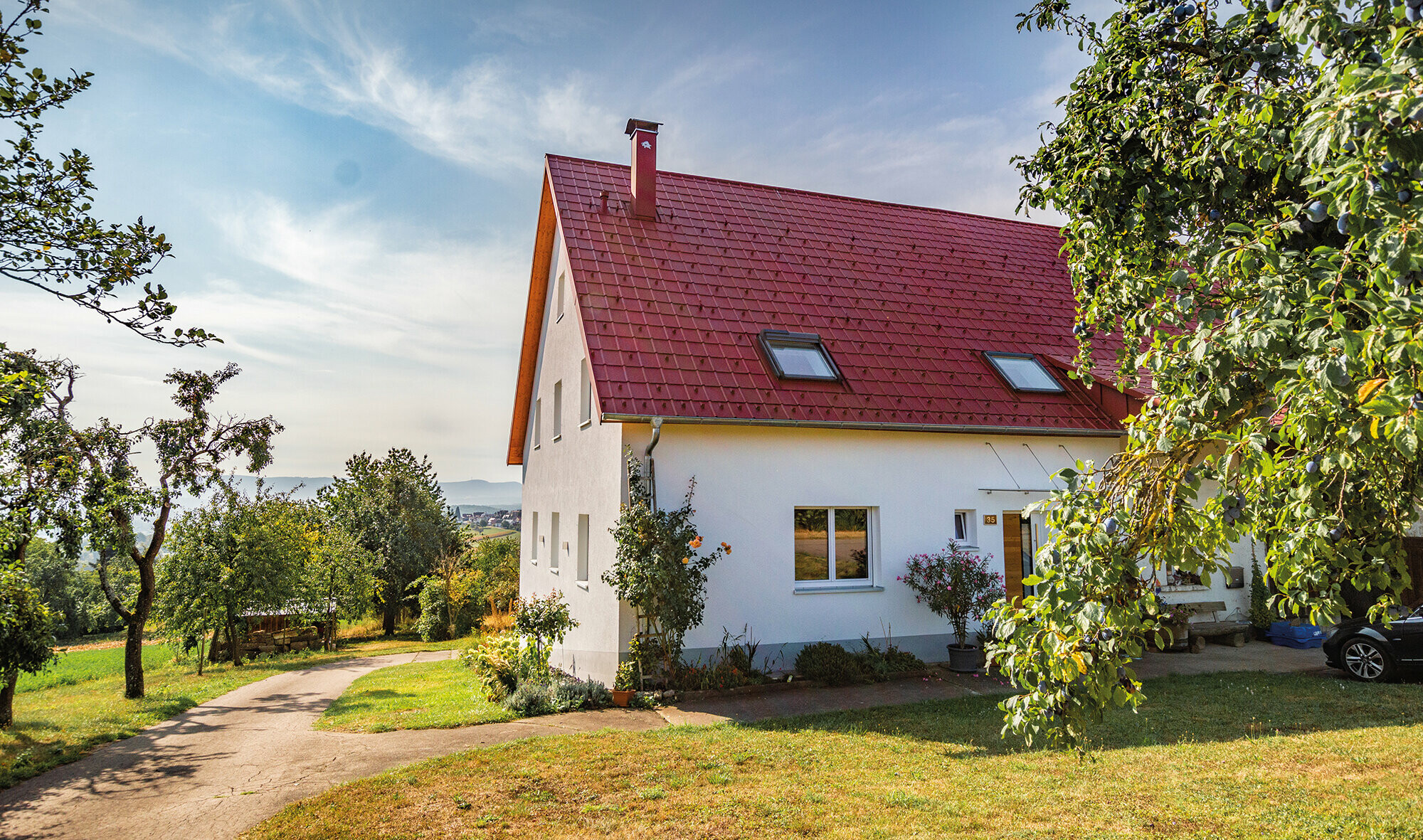 Romantisches Häuschen am land mit viel Bäumen und Sträuchern. Eingedeckt mit einem PREFA Dach in Oxydrot.