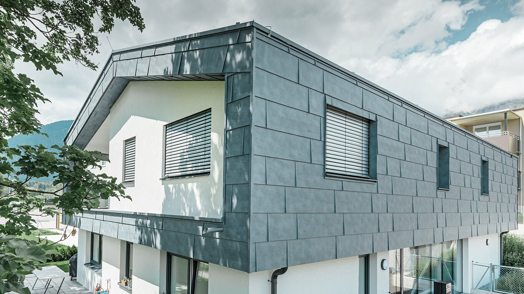 Modernes Einfamilienhaus ohne Dachvorsprung; Die obere Etage wurde mit PREFA Fassadenpaneelen FX.12 in Steingrau verkleidet, der Rest der Fassade wurde weiß verputzt.