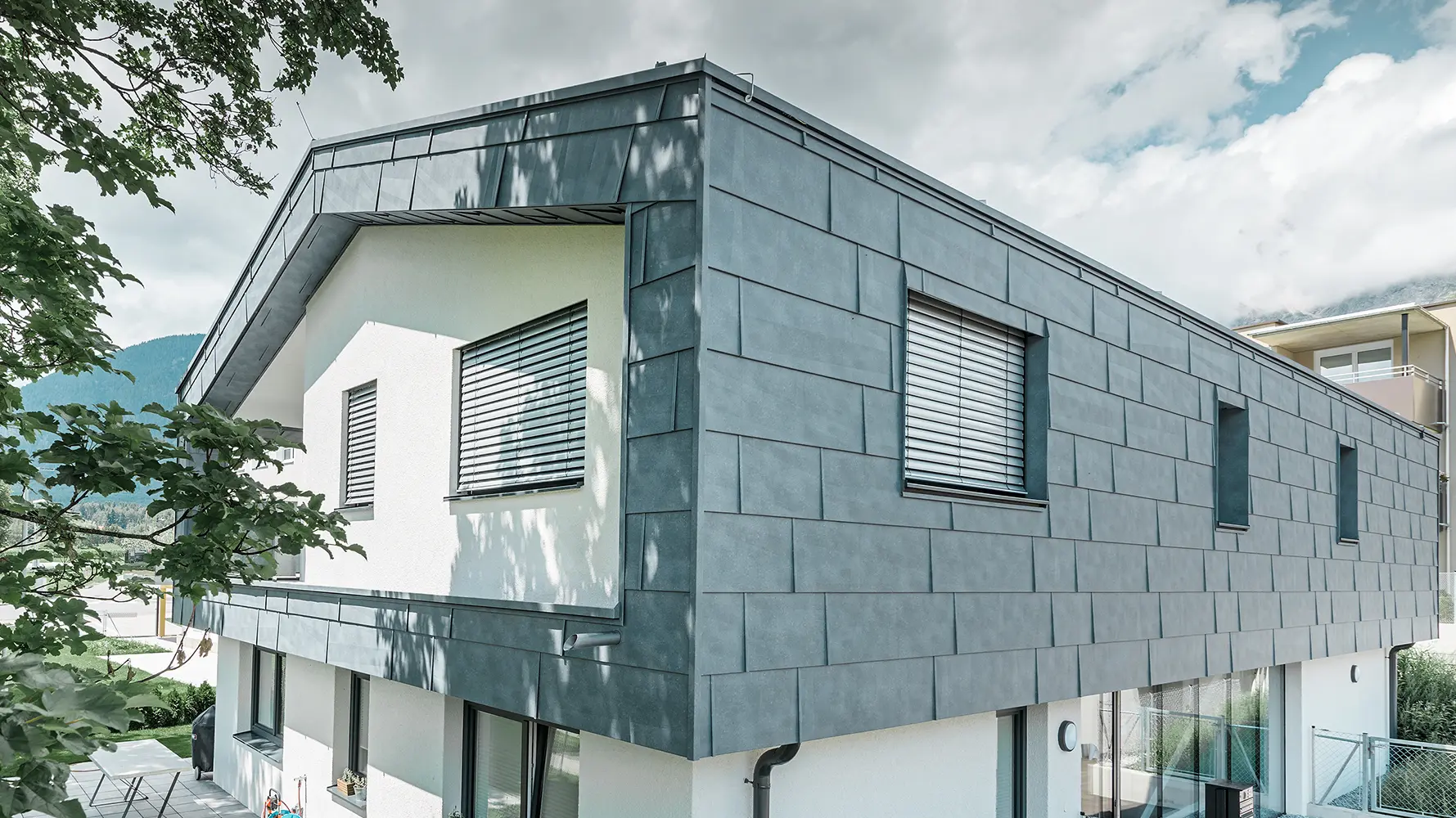 Modernes Einfamilienhaus ohne Dachvorsprung; Die obere Etage wurde mit PREFA Fassadenpaneelen FX.12 in Steingrau verkleidet, der Rest der Fassade wurde weiß verputzt.
