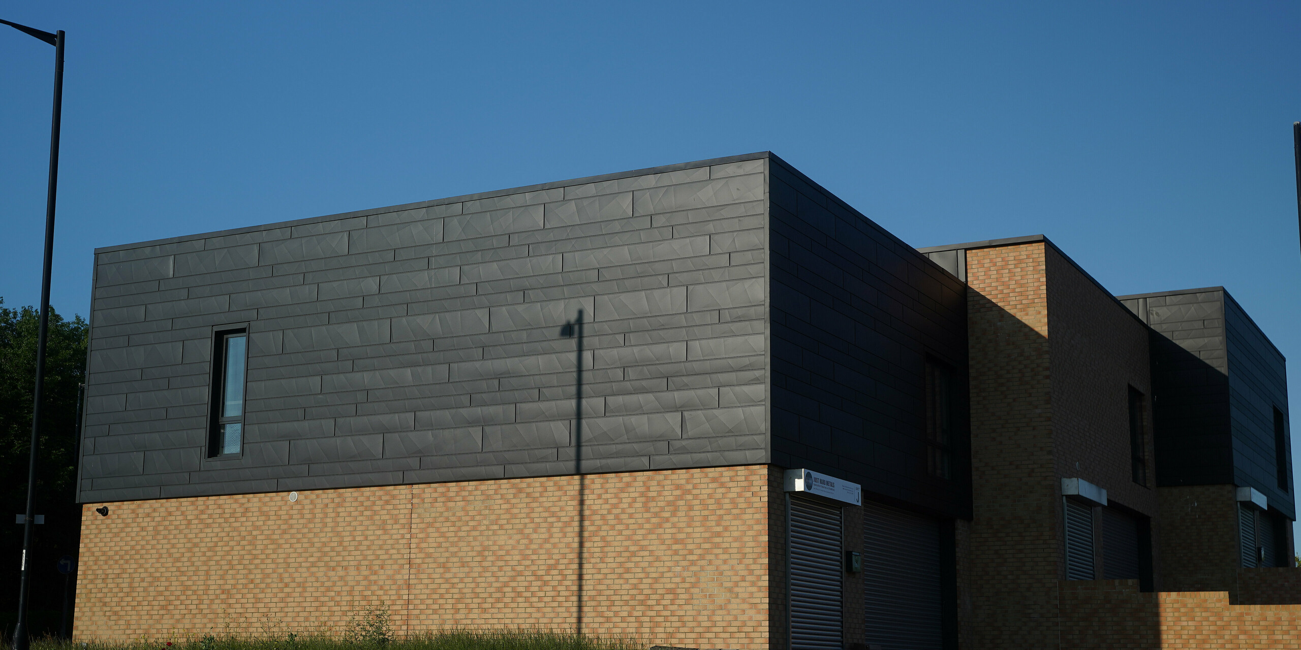 Firmengebäude in Sunderland mit Fassade aus PREFA Siding.X in P.10 Anthrazit und Ziegeln