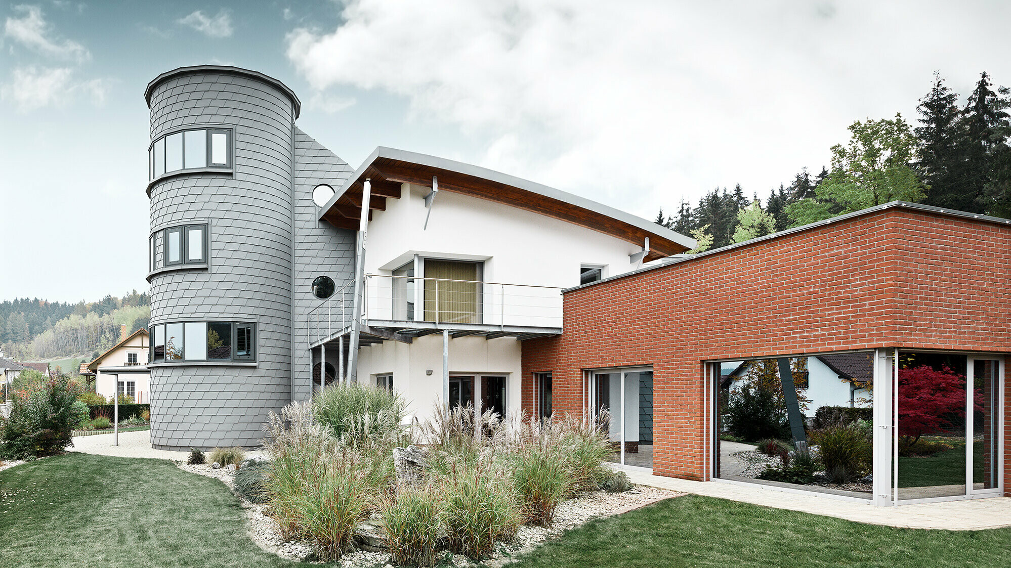 Einfamilienhaus mit Turmzubau, der runde Turm ist mit der PREFA Wandschindel in Patina Grau verkleidet 