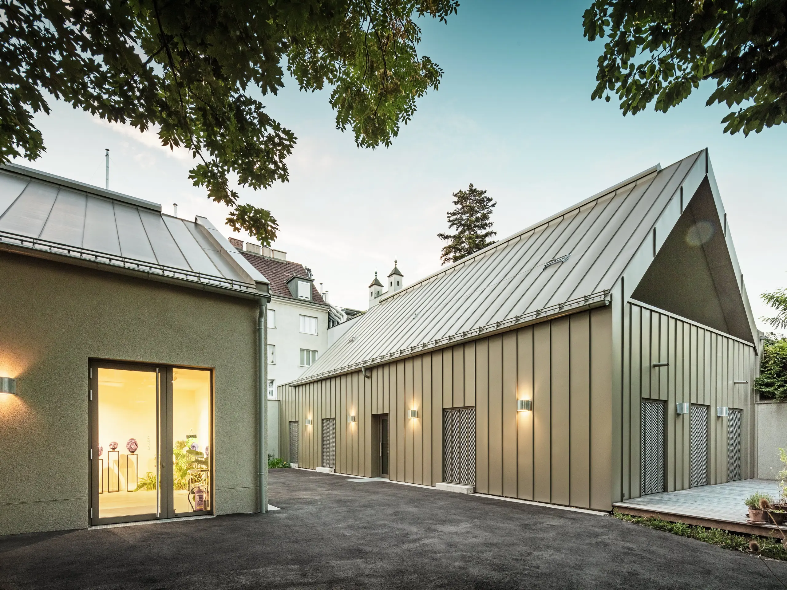 Seitenansicht des Studio Comploj in Wien mit PREFALZ-Aluminiumfassade in P.10 Prefabronze. Das moderne Ensemble aus Glaskunst, Galerie und Wohnraum vereint Handwerkskunst und Architektur.