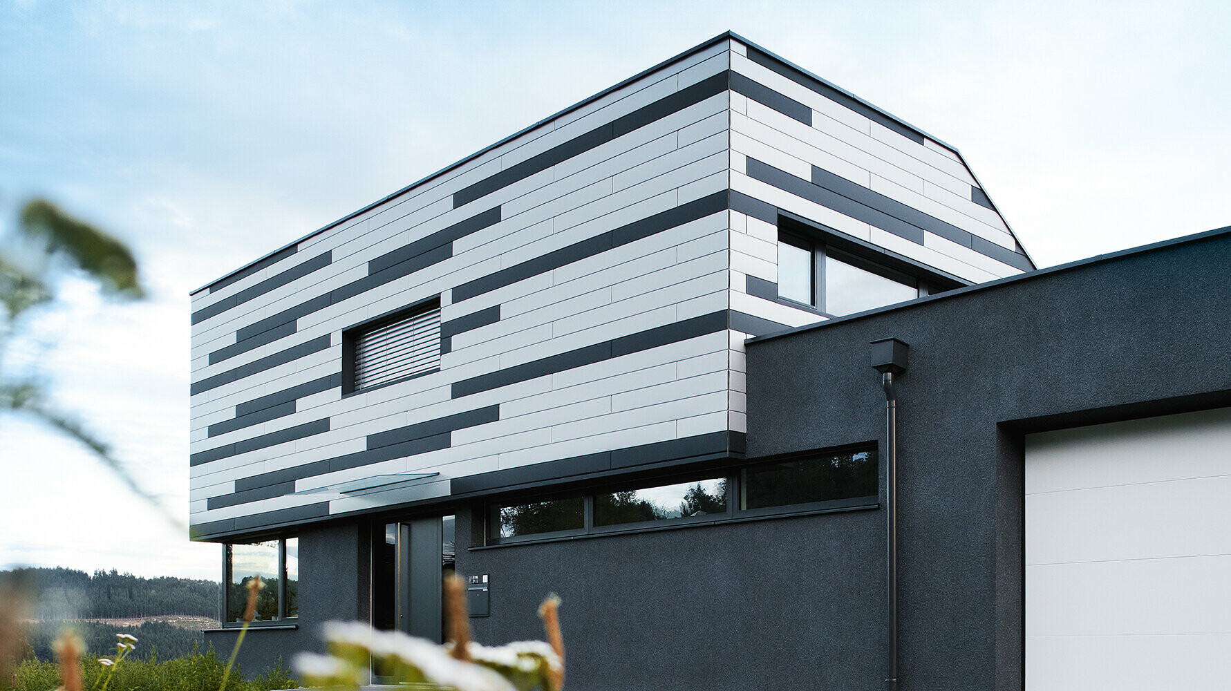 Modernes Einfamilienhaus mit kreativer Fassadengestaltung; Die PREFA Sidings wurden in Silber und Anthrazit matt gemischt verlegt.