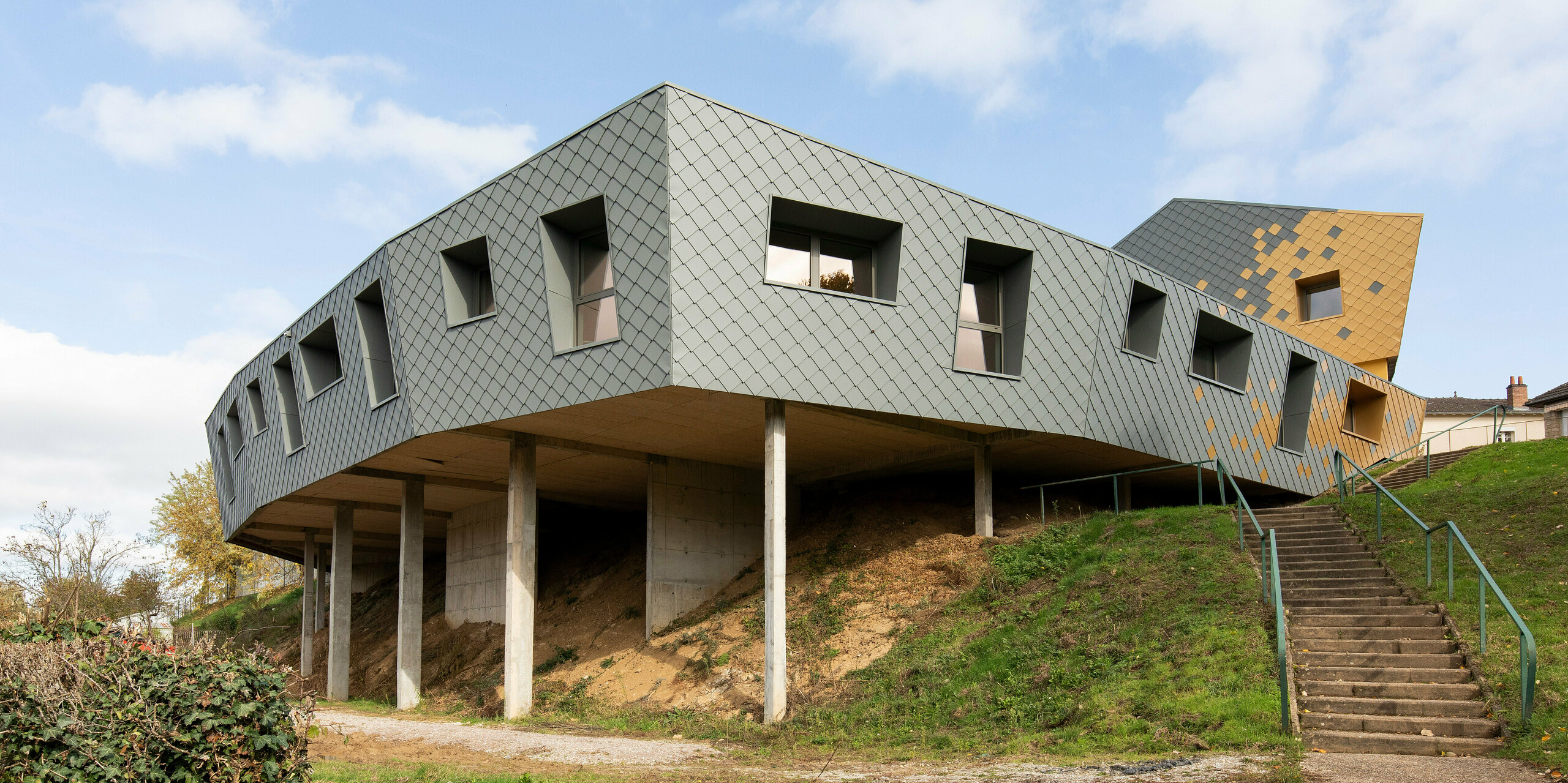 Die Grundschule in Pierre-Buffière wurde mit PREFA Dach- und Wandrauten 29 × 29 ummantelt steht teilweise auf Stelzen