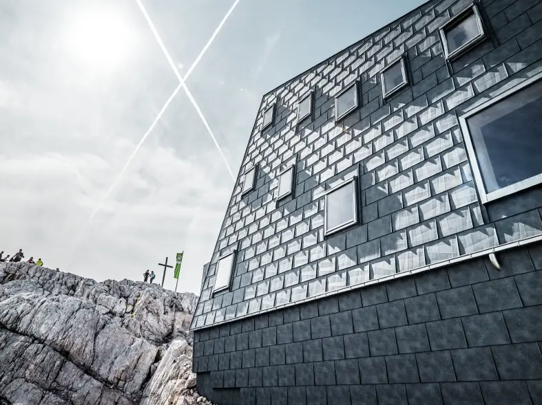 seitliche Ansicht der Seethalerhütte auf 2.740 Metern Höhe vor blauem Himmel, verkleidet mit PREFA Dach- und Fassadenpaneelen FX.12 in P.10 Steingrau