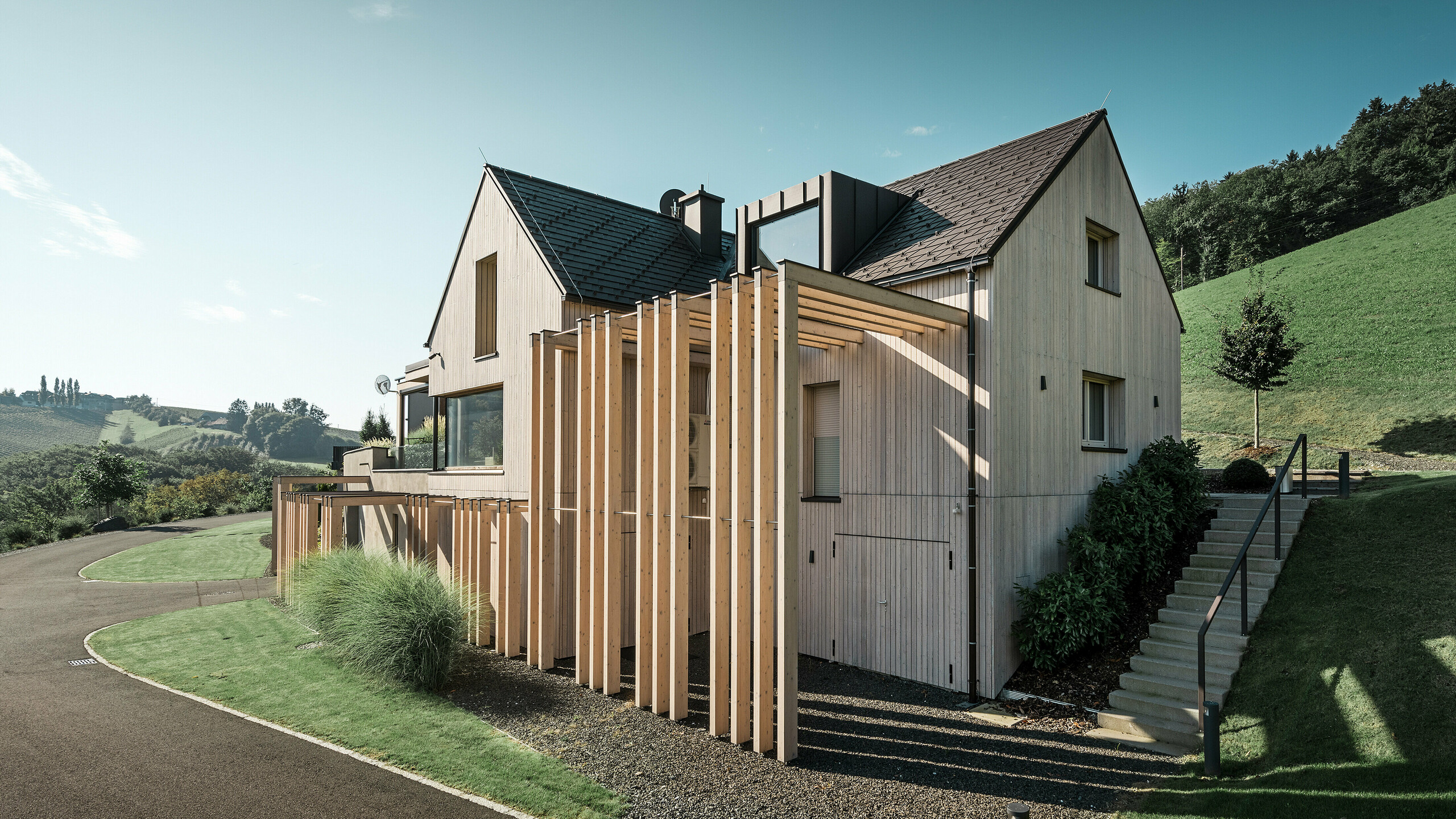Modernes Haus mit Holzfassade und PREFA Dachschindel-Dach in P.10 Nussbraun
