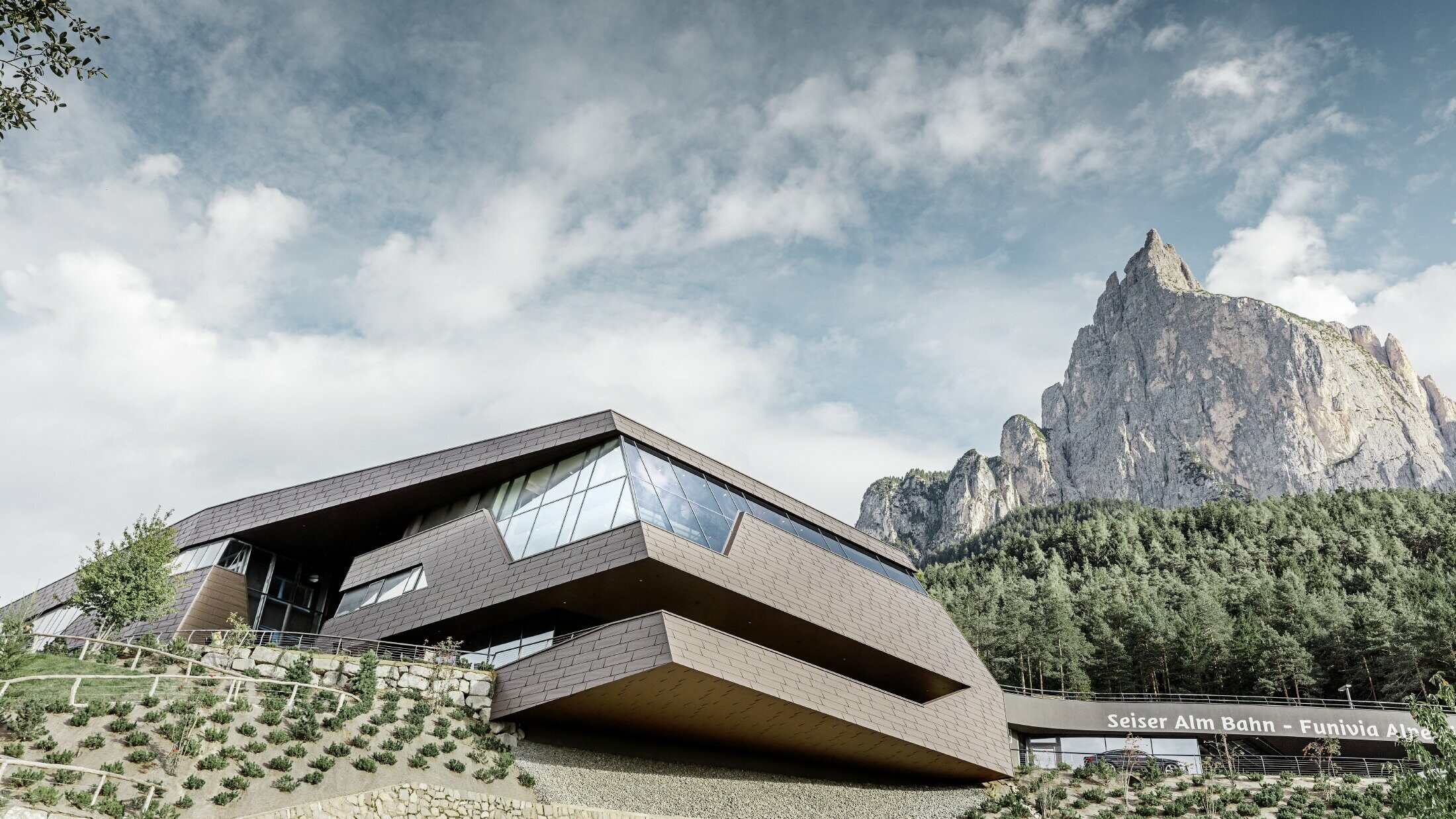neu gestaltete Talstation der Umlaufbahn Seiser Alm, ähnlich der Dolomiten im Hintergrund mit unregelmäßigen Kanten und Oberflächen mit einer Aluminium Fassade in braun von PREFA