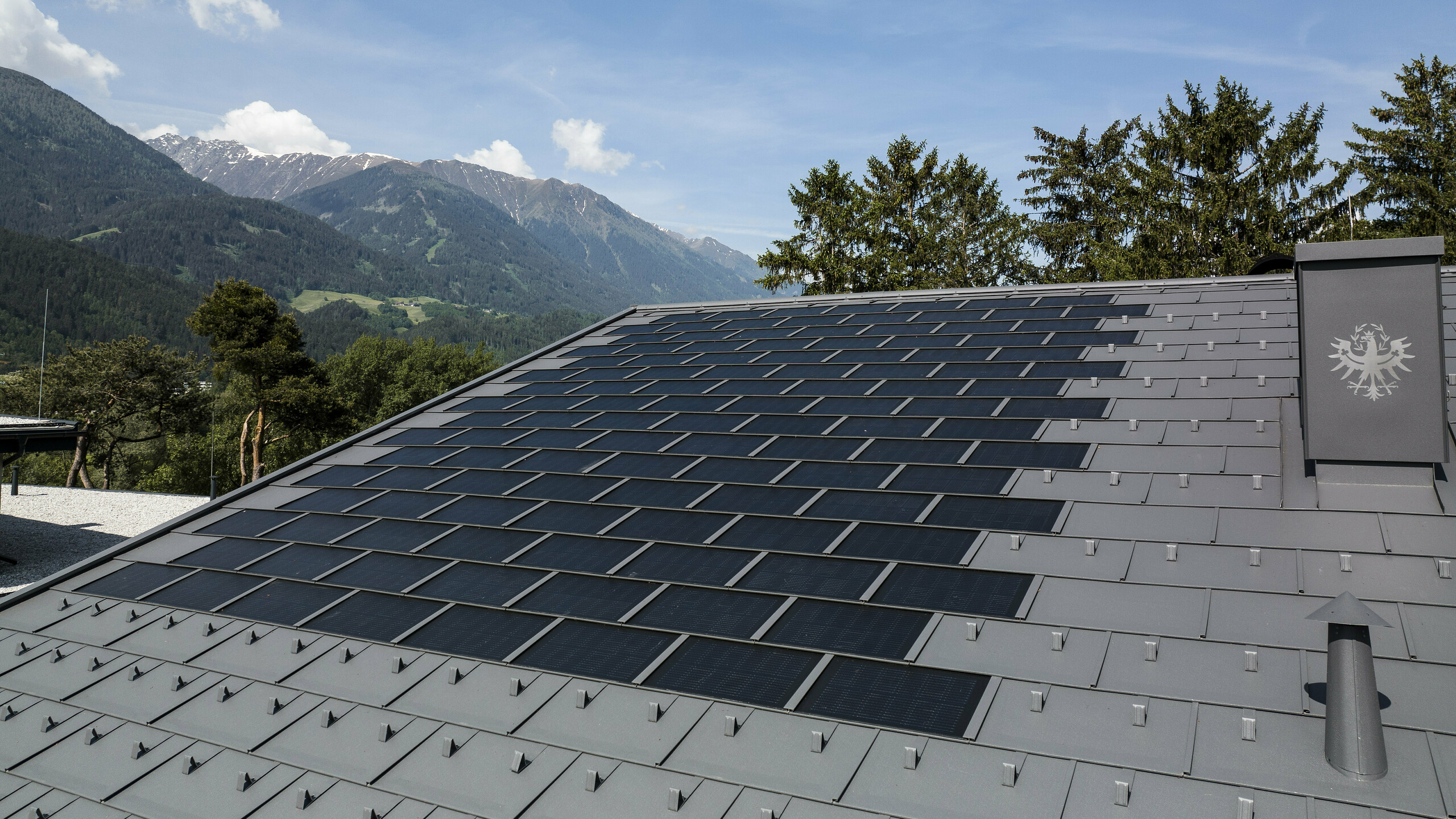 Eine Aufnahme des Daches in Tirol gedeckt mit der PREFA Solardachplatte R.16 in der Farbe P.10 Dunkelgrau