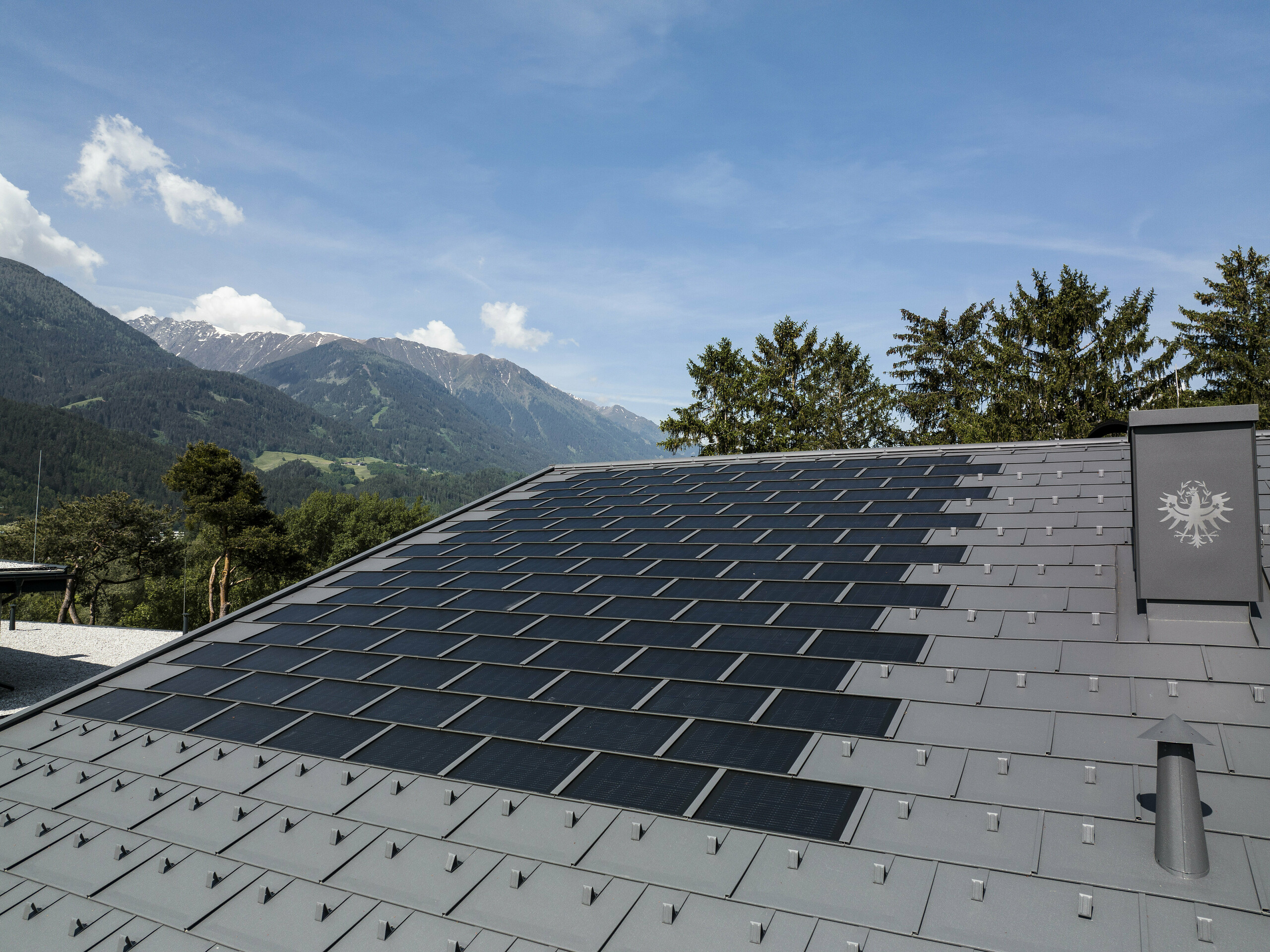 Eine Aufnahme des Daches in Tirol gedeckt mit der PREFA Solardachplatte R.16 in der Farbe P.10 Dunkelgrau