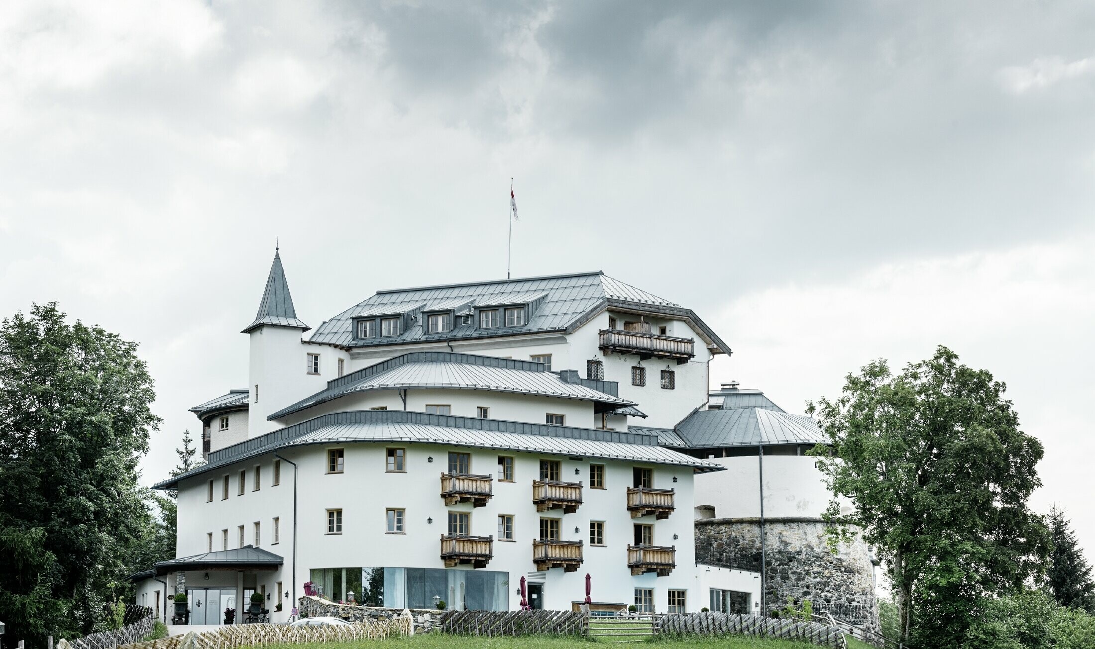 Schloss Mittersill, umgeben von Bäumen und Bergen, mit einem renovierten Prefalz Dach in Steingrau