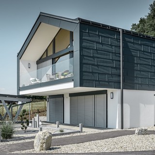 Modernes Mehrfamilienhaust mit einer großen Fensterfront, Dach und Fassade wurden mit dem Dach- und Fassadenpaneel FX.12 in anthrazit von PREFA bekleidet