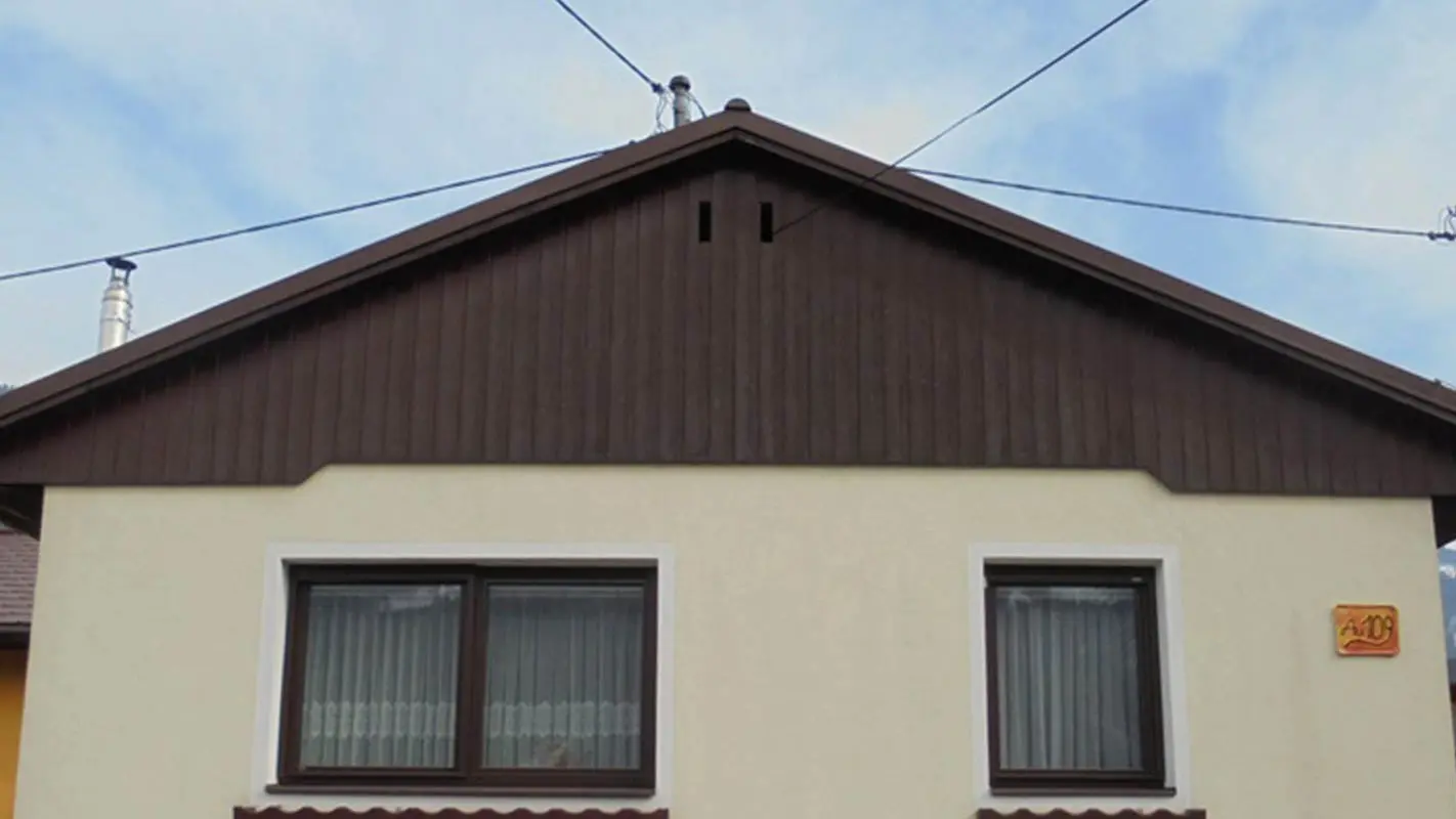 Vor der Fassadensanierung des Giebels mit PREFA Sidings, gelbe Putzfassade und abgewittertes Holz