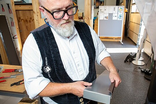 Detailaufnahme eines Aluminiumteils, der für die Laibung im oberen Fensterbereich durch den PREFA Techniker umgekantet wird.