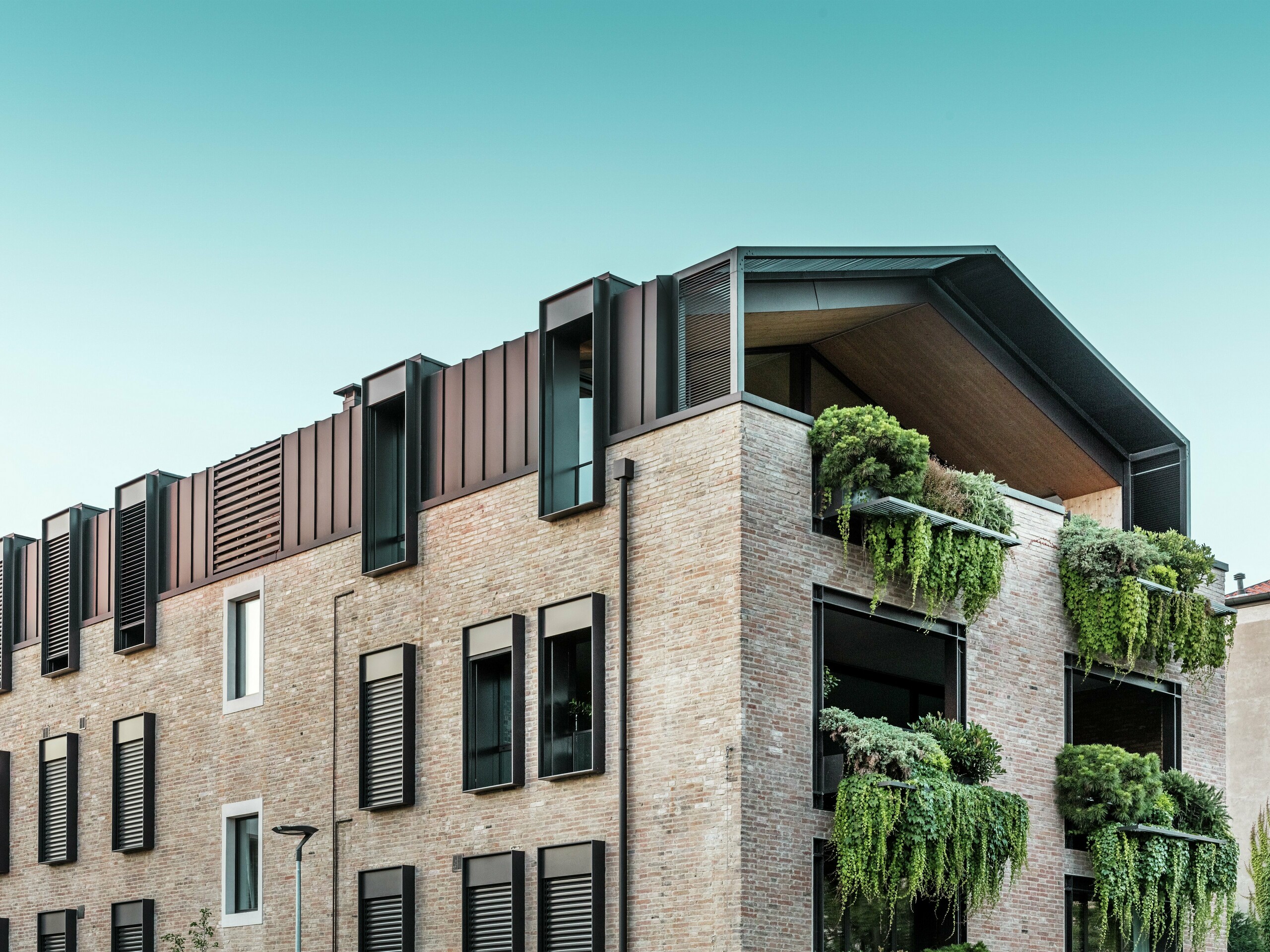 Nachhaltiges Wohnhaus in Italien mit PREFALZ Aluminiumdach in P.10 Nussbraun und hängenden Gärten an der Südfassade – klimaaktive Architektur mit Backstein und Begrünung.