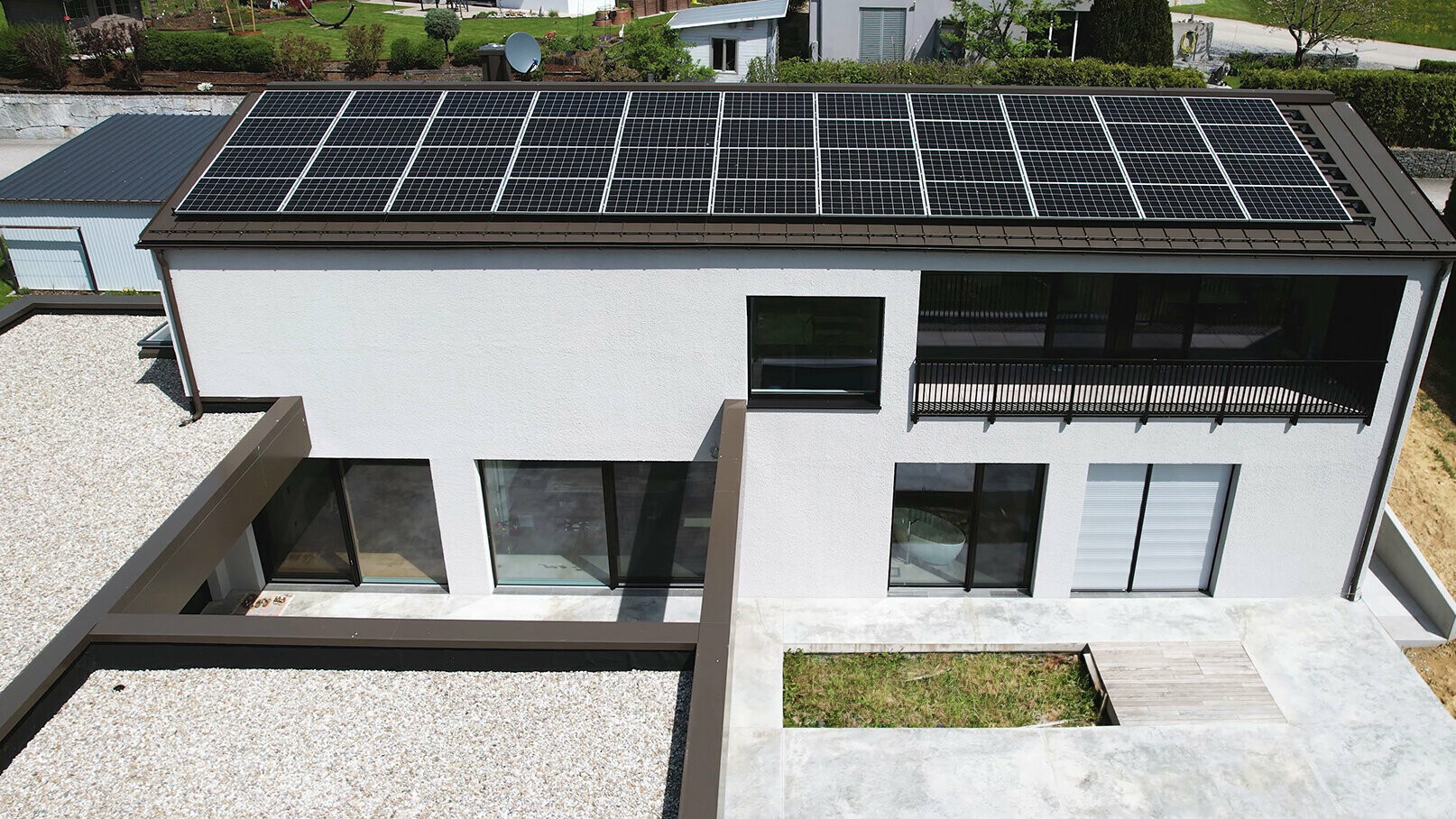 Blick auf das Haus der Familie Razenberger und auf die Terrasse. Im Hintergrund ist die Photovoltaikanlage am Dach zu sehen.